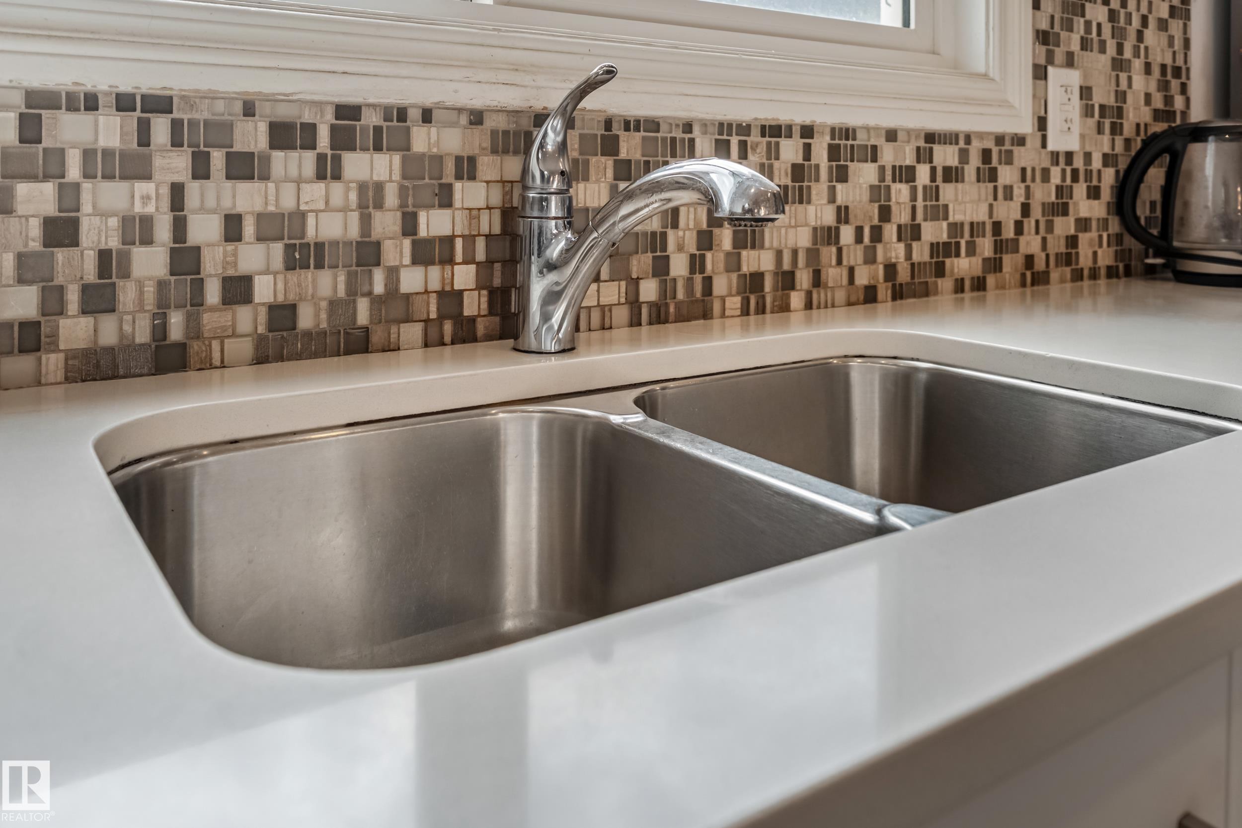 Double basin stainless steel sink with a polished chrome faucet, set into a white countertop - 8131 Chappelle Way, Edmonton, AB - Indoor Photo Showing Kitchen With Double Sink