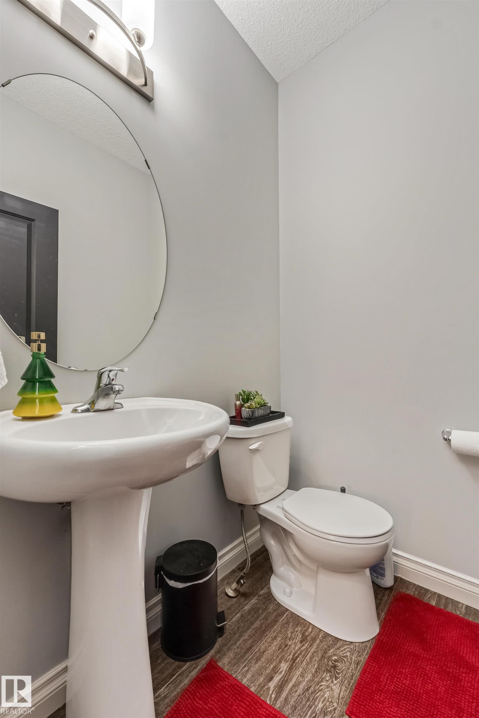 Pedestal sink with chrome faucet, circular mirror, and overhead vanity lighting - 8131 Chappelle Way, Edmonton, AB - Indoor Photo Showing Bathroom