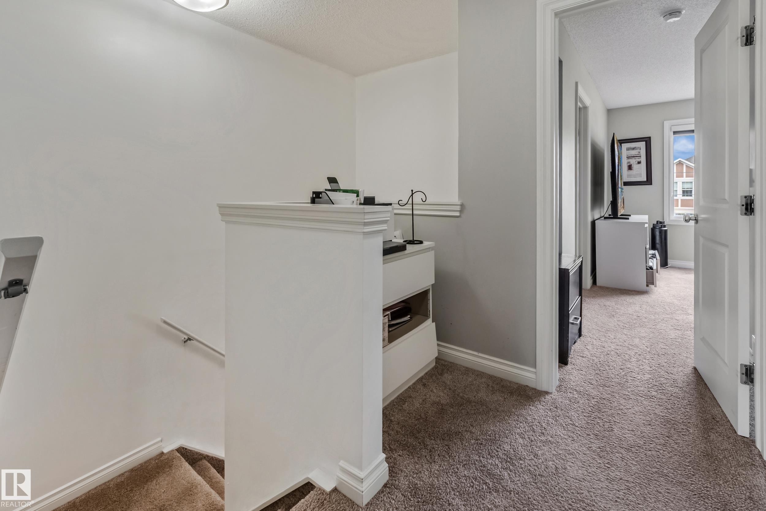 Carpeted staircase with white handrail and trim, leading to a carpeted hallway with light gray walls and white trim - 8131 Chappelle Way, Edmonton, AB - Indoor Photo Showing Other Room