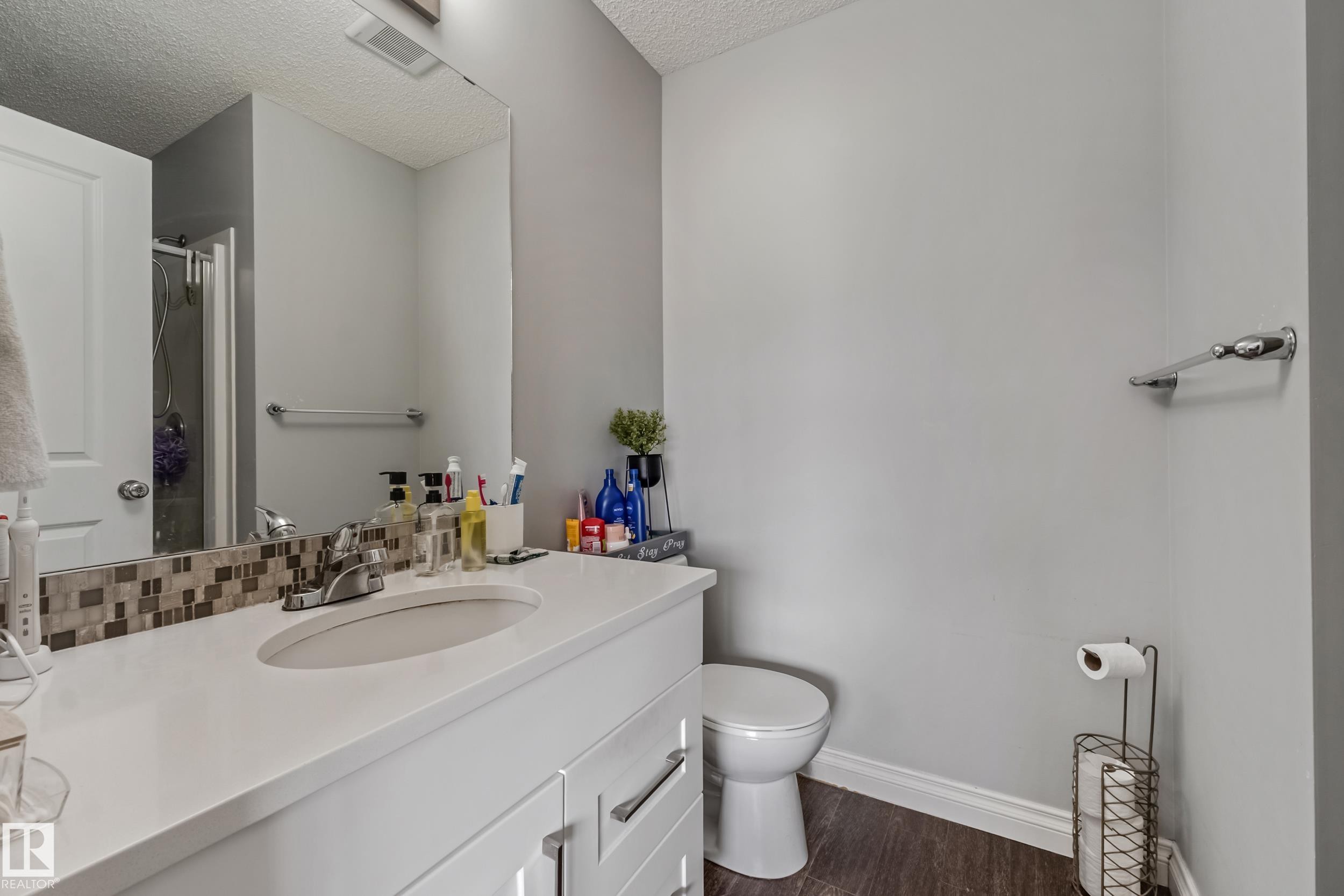 Bathroom featuring a white vanity with an integrated sink, mosaic tile backsplash, and a large mirror - 8131 Chappelle Way, Edmonton, AB - Indoor Photo Showing Bathroom