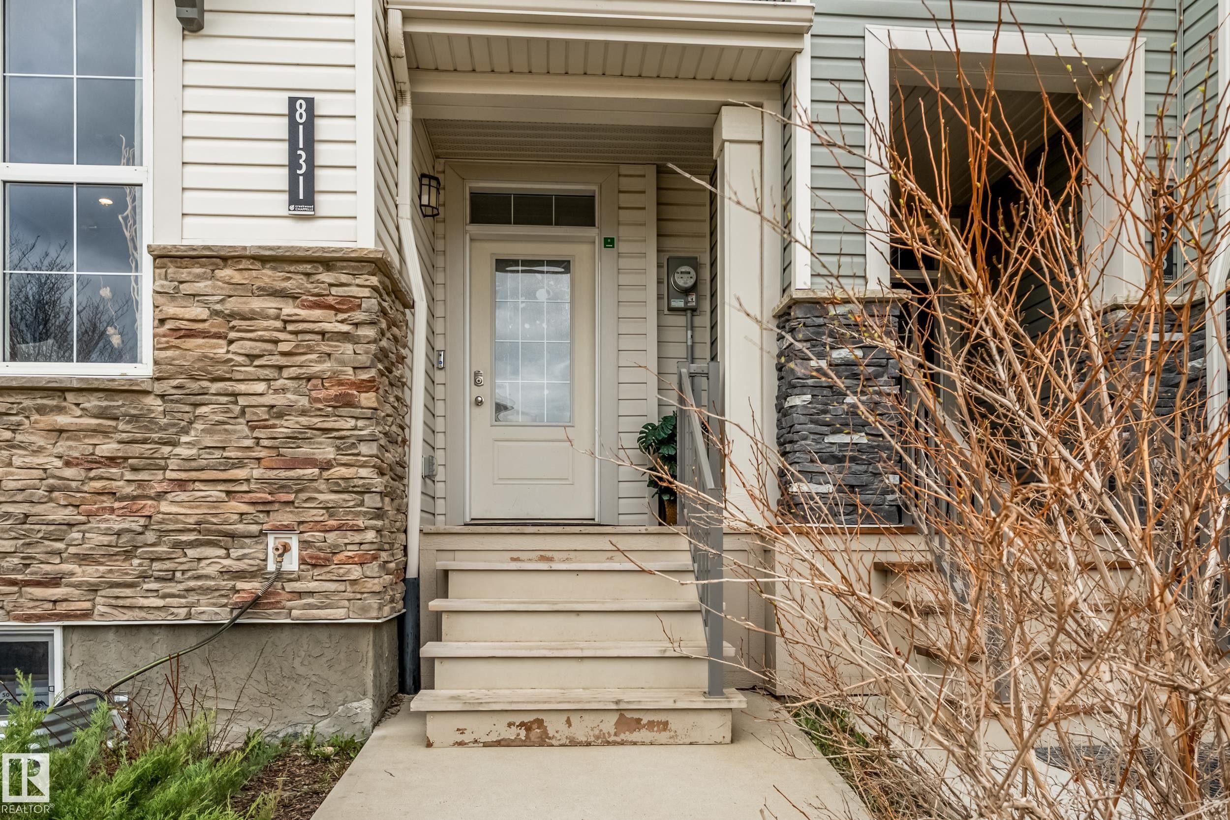 Inviting front entry featuring a paneled door with decorative glass inserts, a covered porch, and a vertical house number display - 8131 Chappelle Way, Edmonton, AB - Outdoor