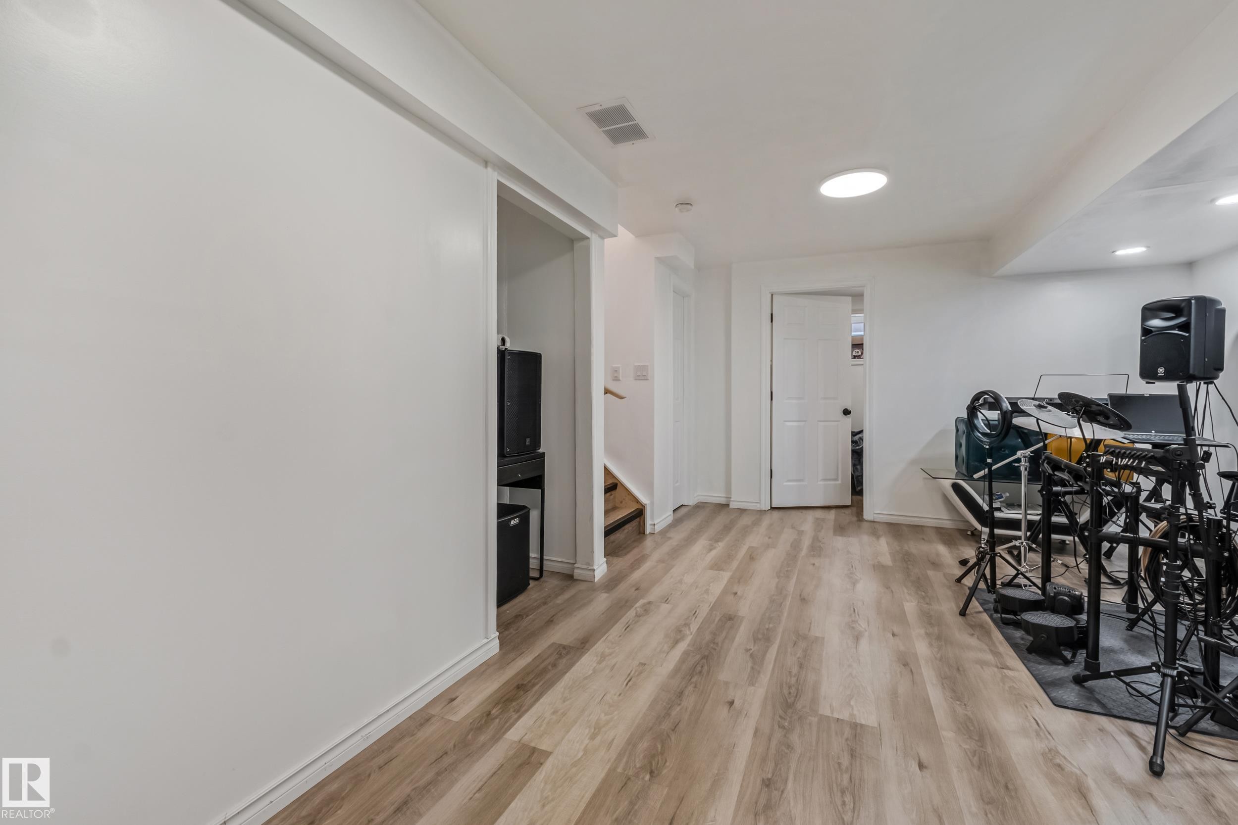 Finished lower level with wood-finish flooring, recessed lighting, and a white interior door - 8131 Chappelle Way, Edmonton, AB - Indoor Photo Showing Other Room