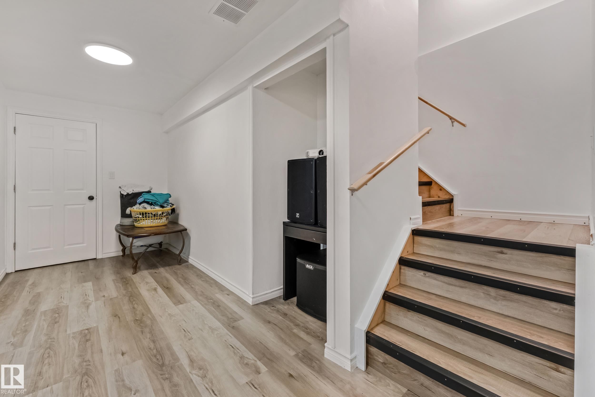 Light wood-finish flooring extending from the hallway to the staircase - 8131 Chappelle Way, Edmonton, AB - Indoor Photo Showing Other Room