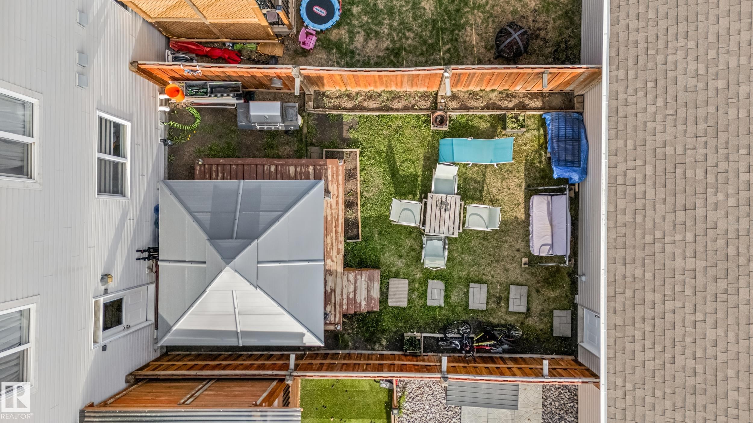Expansive backyard featuring a shaded patio area, a wood-decked lower level, natural grass, and a wood privacy fence - 8131 Chappelle Way, Edmonton, AB - With Exterior