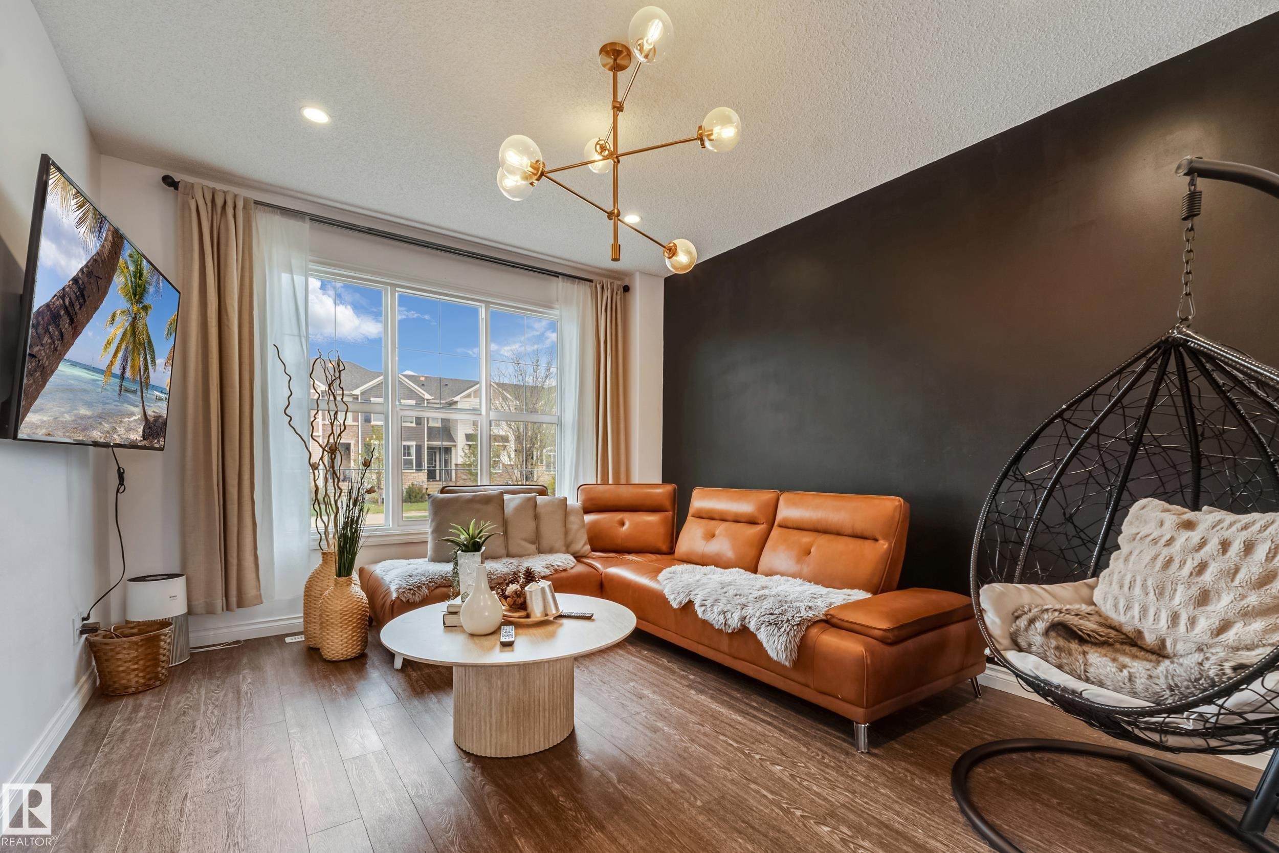 Living area featuring wood-finish flooring, a large multi-pane window, and recessed lighting - 8131 Chappelle Way, Edmonton, AB - Indoor Photo Showing Living Room