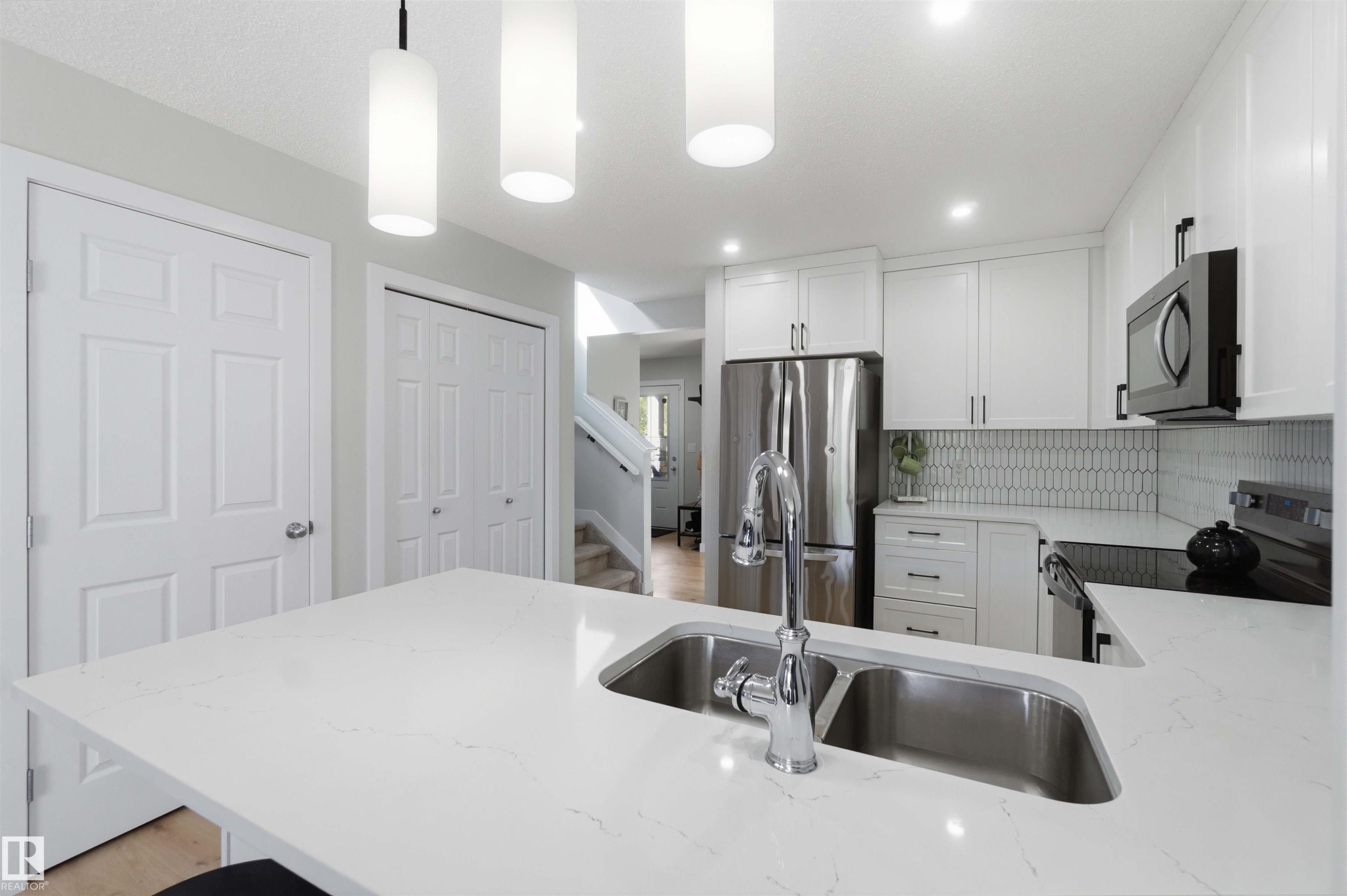 Kitchen featuring white cabinetry, stainless steel appliances, a dual basin sink, and pendant lighting - 5129 Lark Crescent, Edmonton, AB - Indoor Photo Showing Kitchen With Double Sink With Upgraded Kitchen