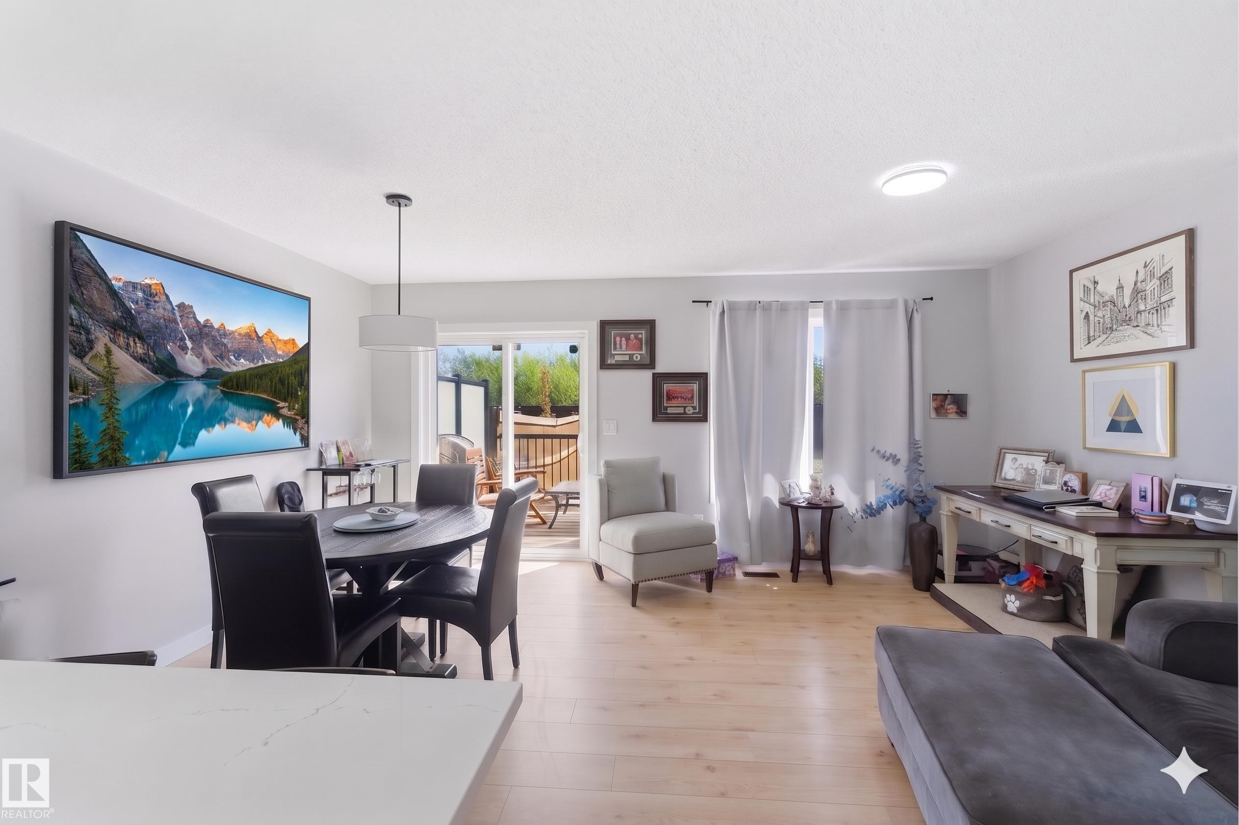 Open-concept living area featuring wood-finish flooring, recessed lighting, and sliding glass doors leading to an exterior deck - 5129 Lark Crescent, Edmonton, AB - Indoor