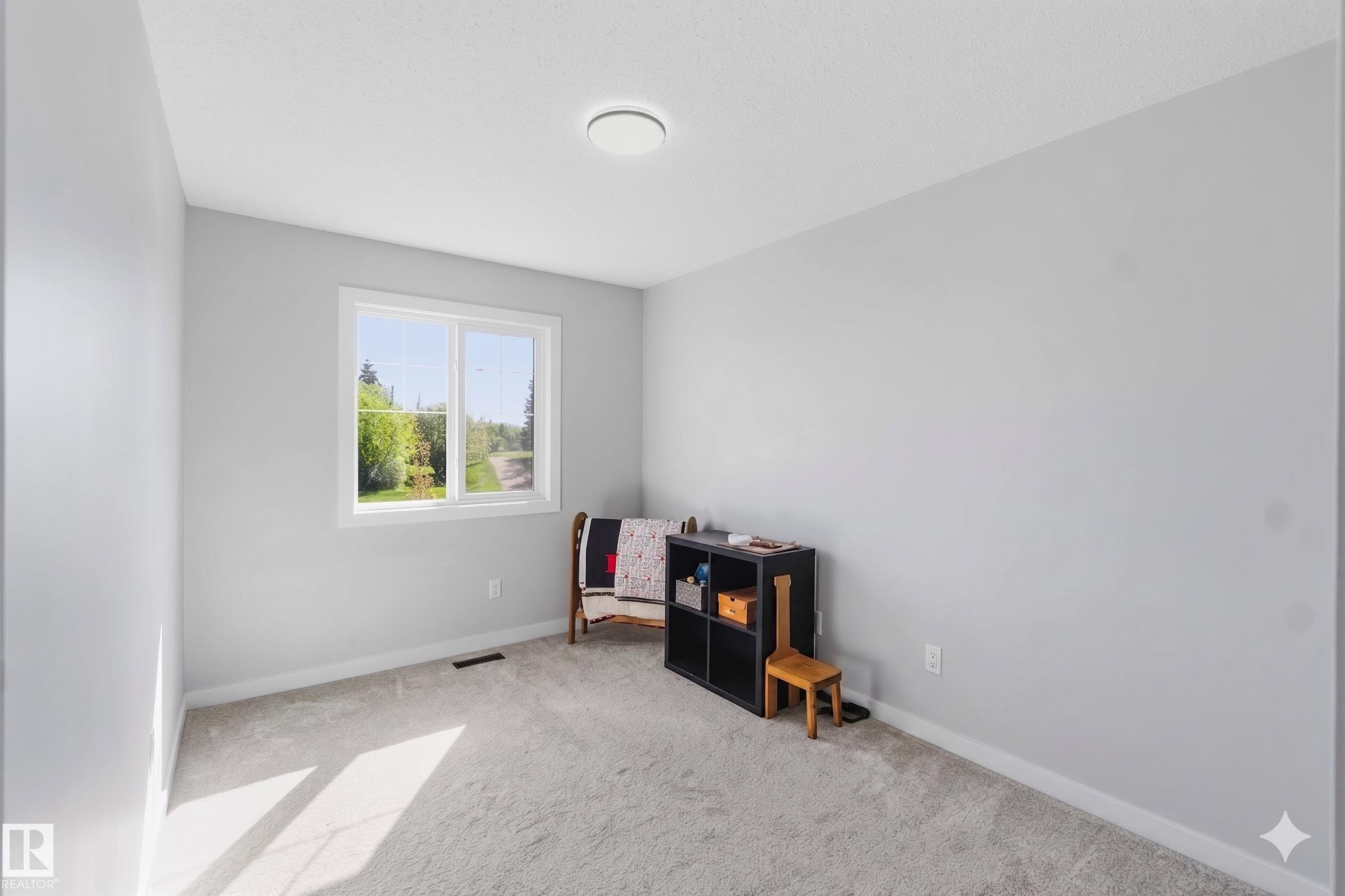 Light gray painted room featuring a double window with white trim, gray carpet, white baseboards, and a flush-mount ceiling light fixture - 5129 Lark Crescent, Edmonton, AB - Indoor