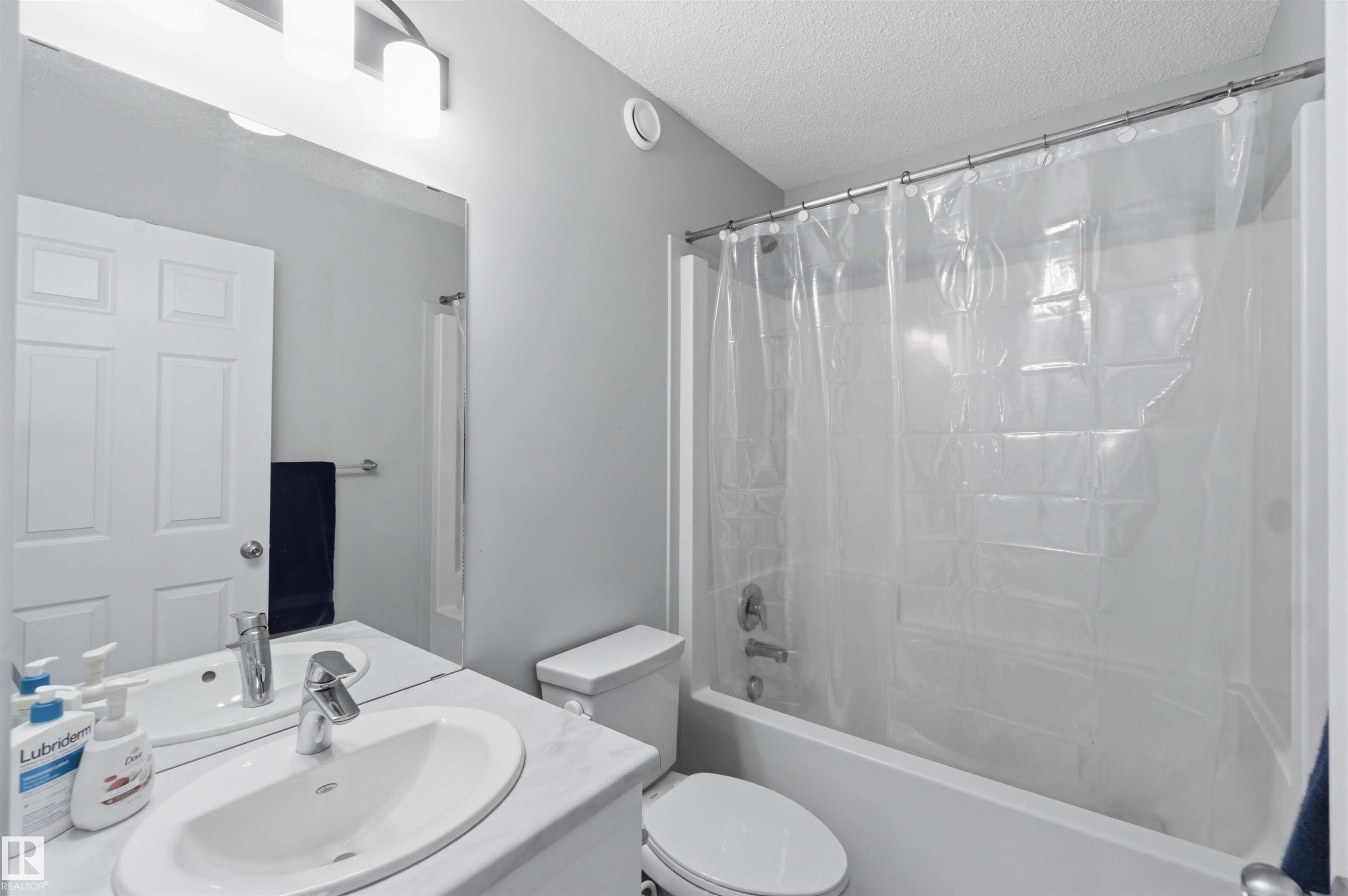 Bathroom featuring a single vanity with an oval basin sink, a wall-mounted mirror, and a combination shower-bathtub with a chrome fixture - 5129 Lark Crescent, Edmonton, AB - Indoor Photo Showing Bathroom