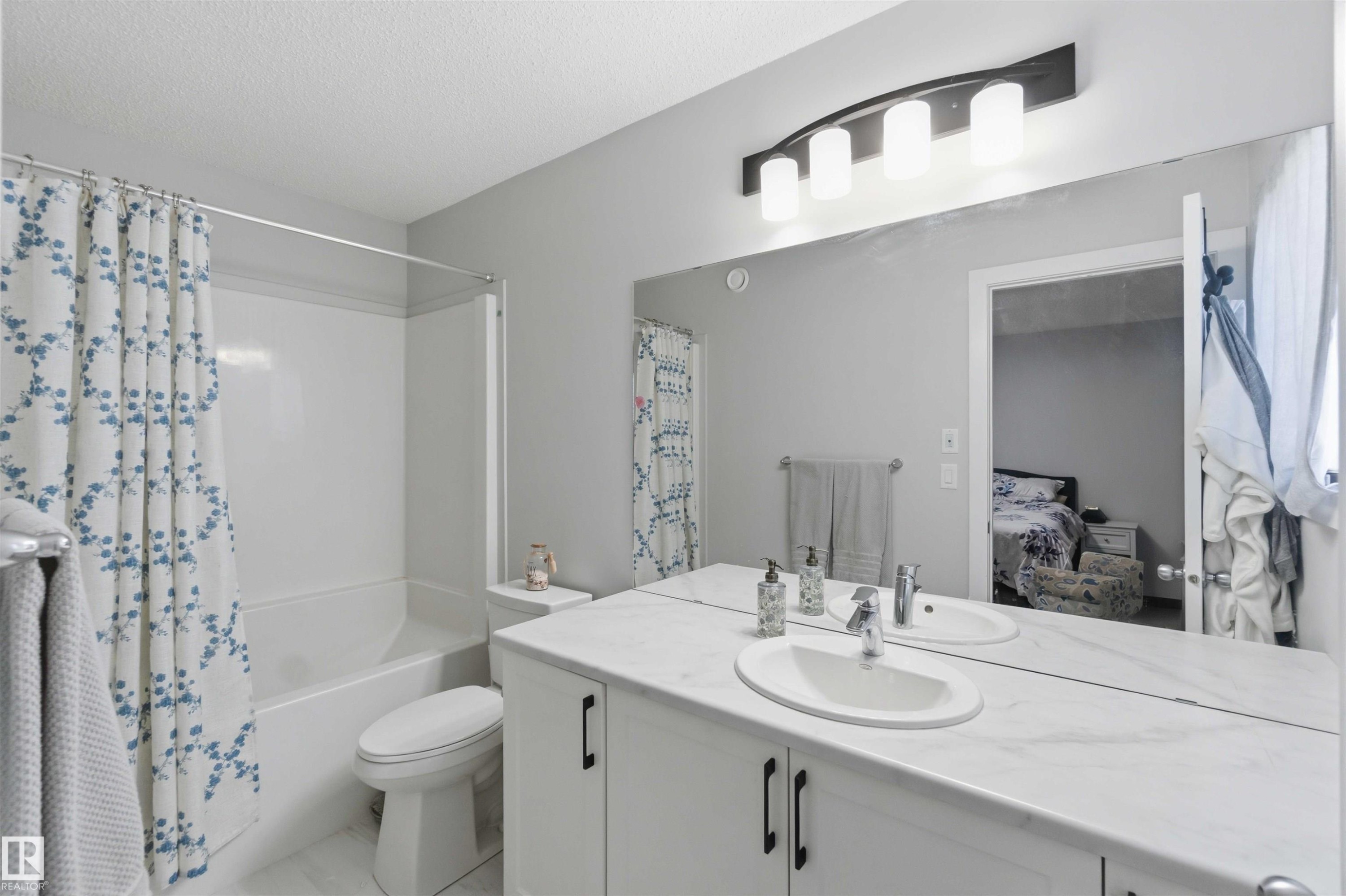 Dual sink vanity with stone-finish countertop - 5129 Lark Crescent, Edmonton, AB - Indoor Photo Showing Bathroom