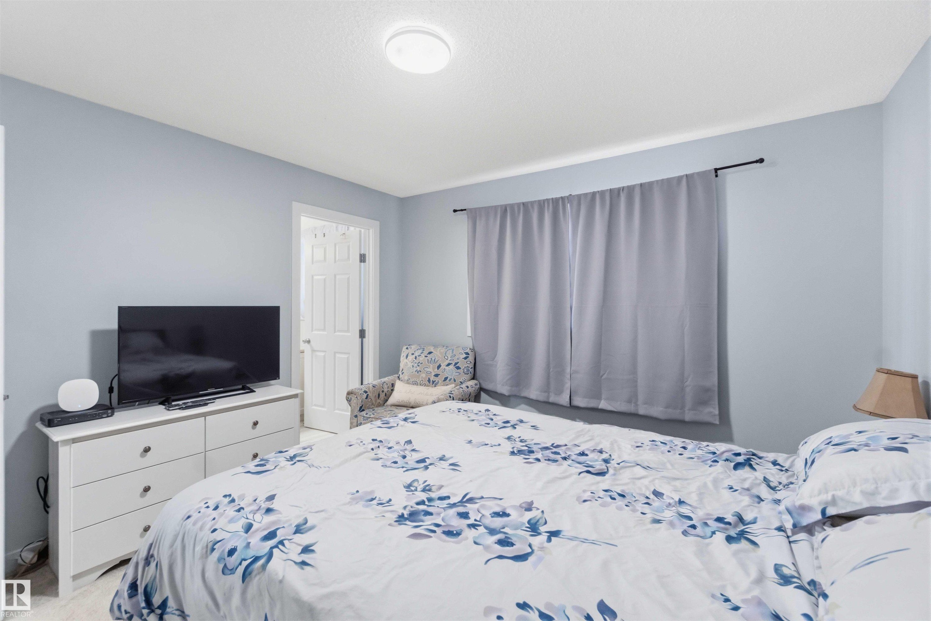 Room featuring light blue walls, a textured white ceiling, and a white six-drawer dresser with dark hardware - 5129 Lark Crescent, Edmonton, AB - Indoor Photo Showing Bedroom