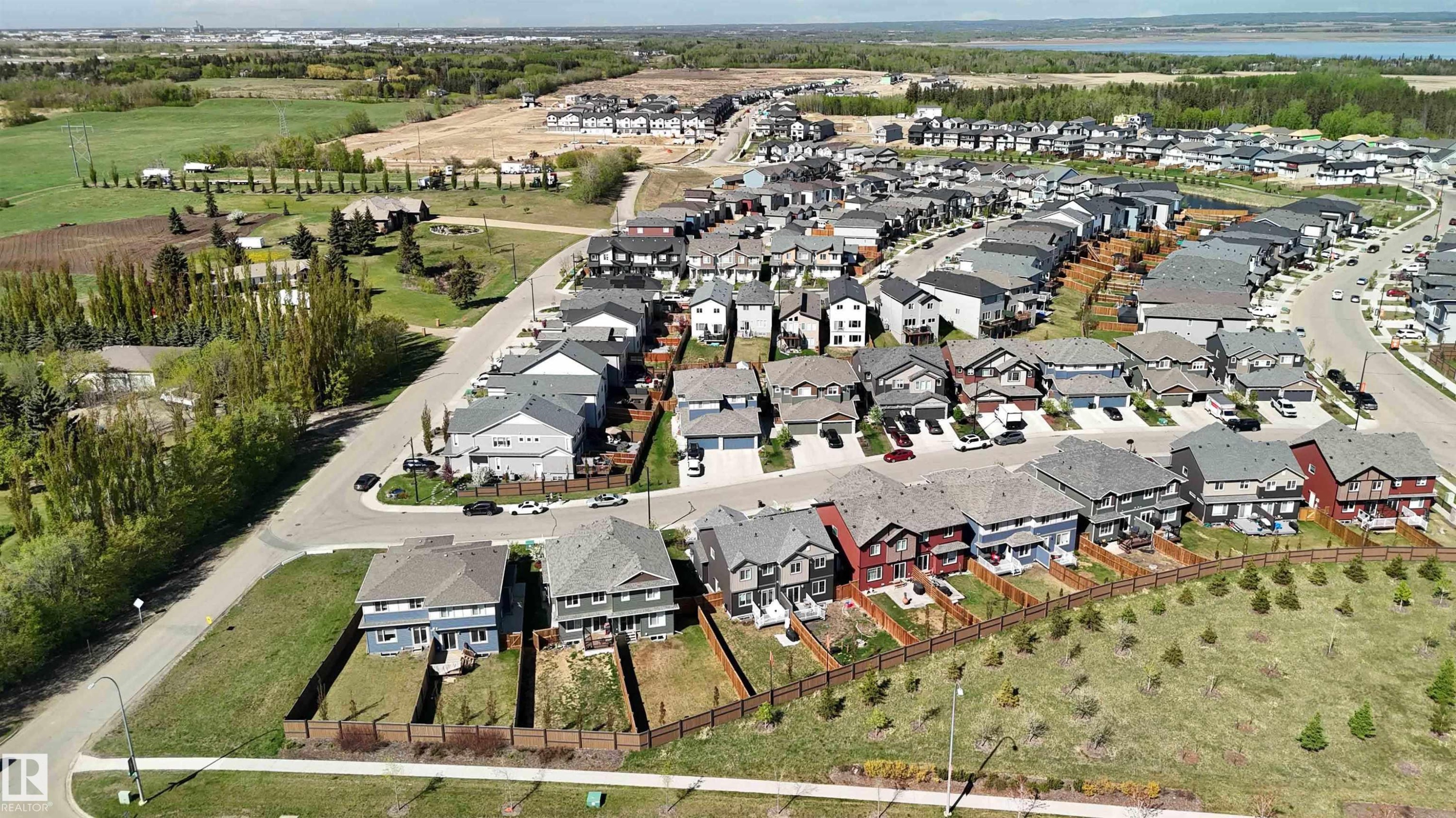 Newer construction development featuring multiple single-family residences with varied architectural styles, paved streets, and a mix of mature and newly planted trees - 5129 Lark Crescent, Edmonton, AB - Outdoor With View