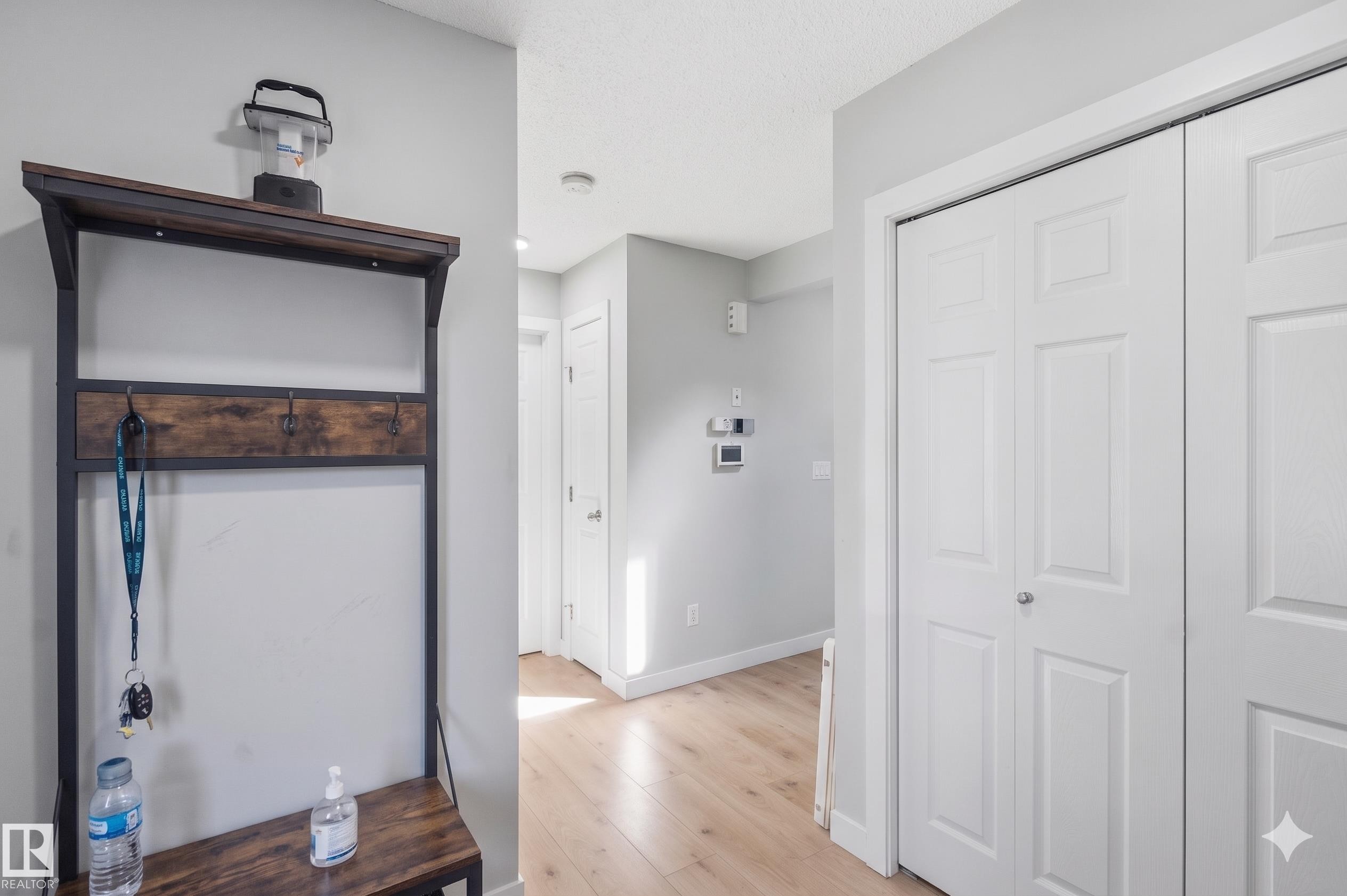 Entryway featuring light gray walls, wood-finish flooring, white trim, and a white bi-fold closet door - 5129 Lark Crescent, Edmonton, AB - Indoor Photo Showing Other Room