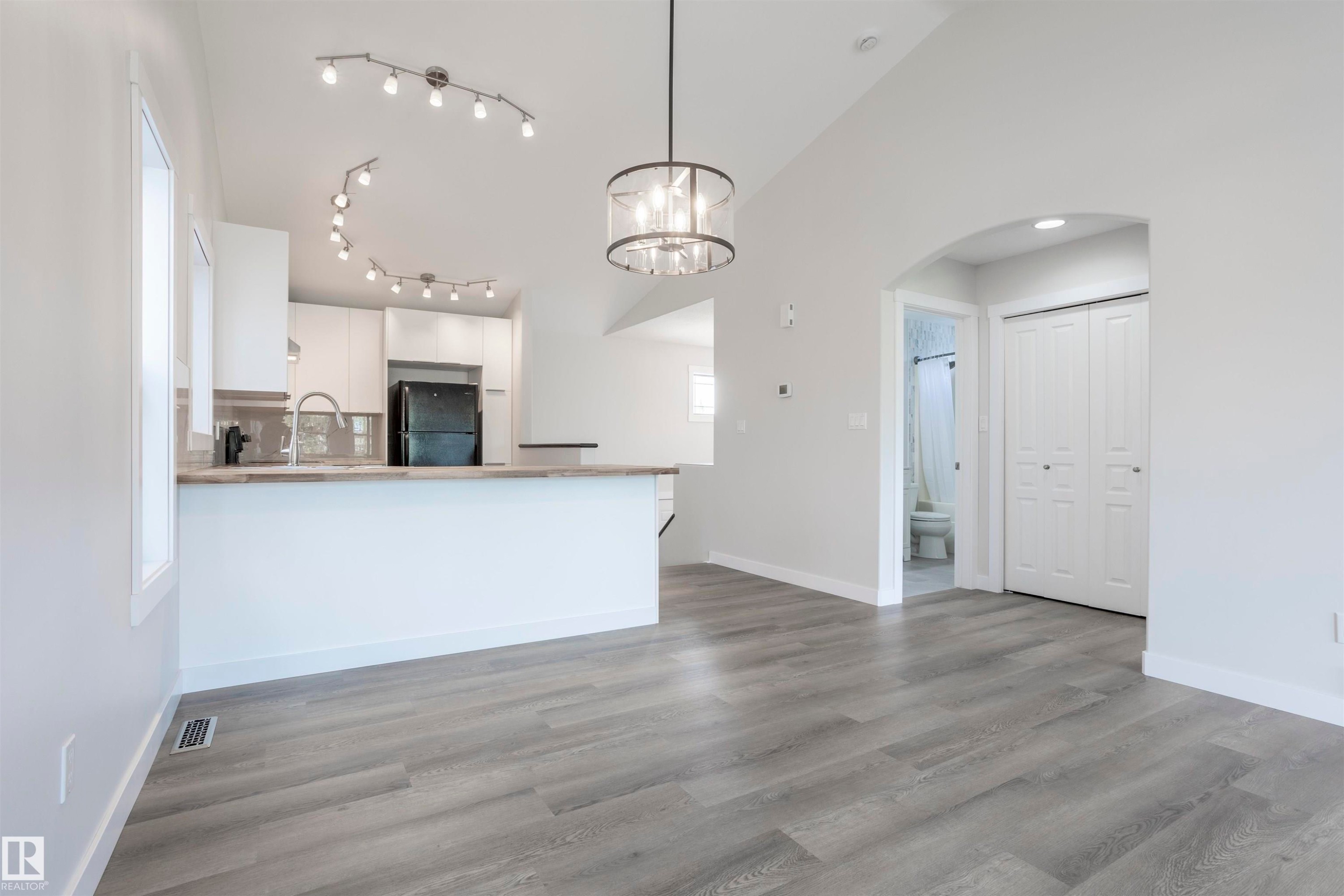 Open-concept living area with wood-finish flooring, a contemporary chandelier, and recessed lighting - 738 Kananaskis Drive, Devon, AB - Indoor Photo Showing Kitchen