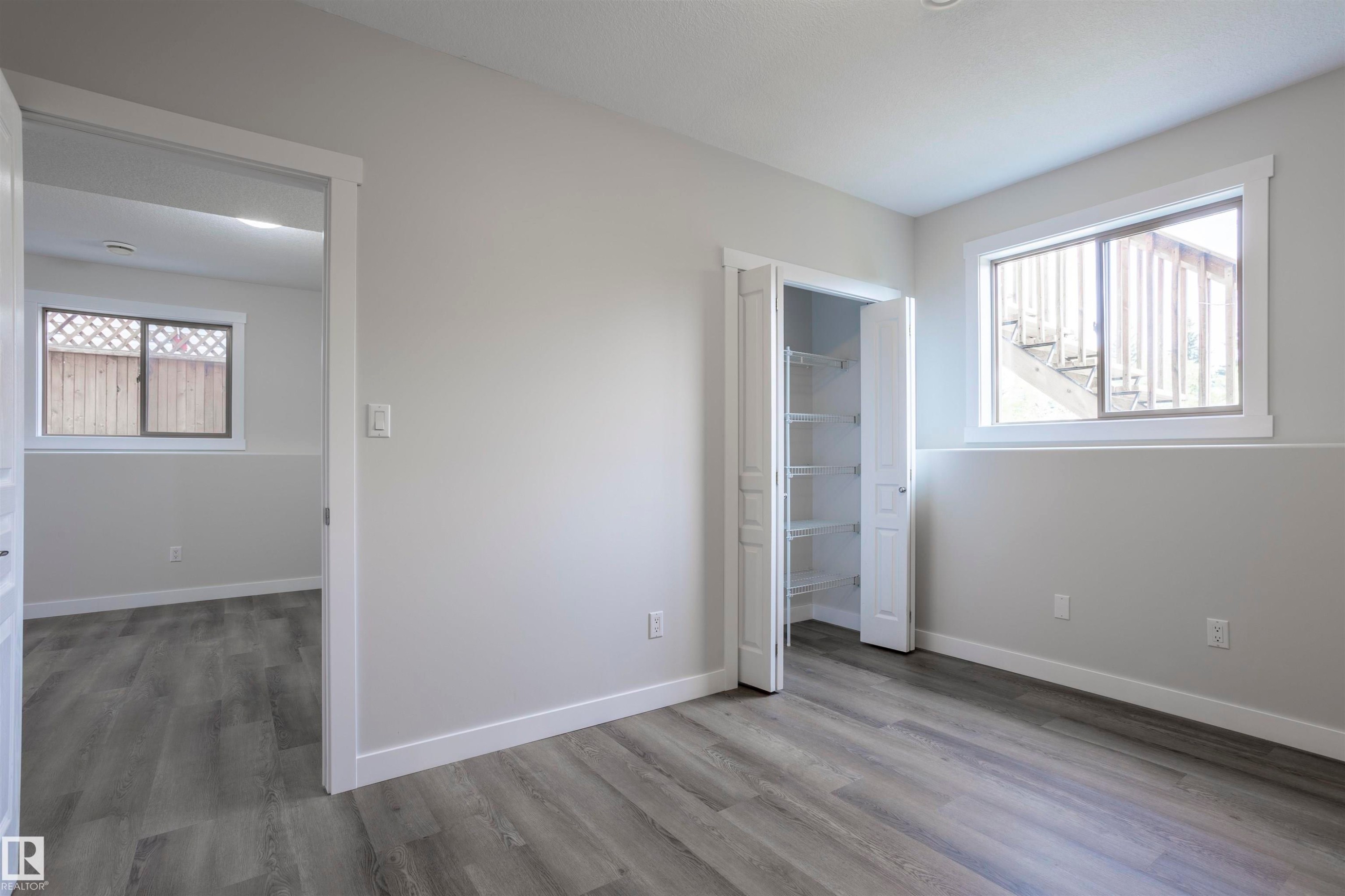 Interior space featuring wood-finish flooring, light gray walls, white trim, and a window with a white frame - 738 Kananaskis Drive, Devon, AB - Indoor Photo Showing Other Room