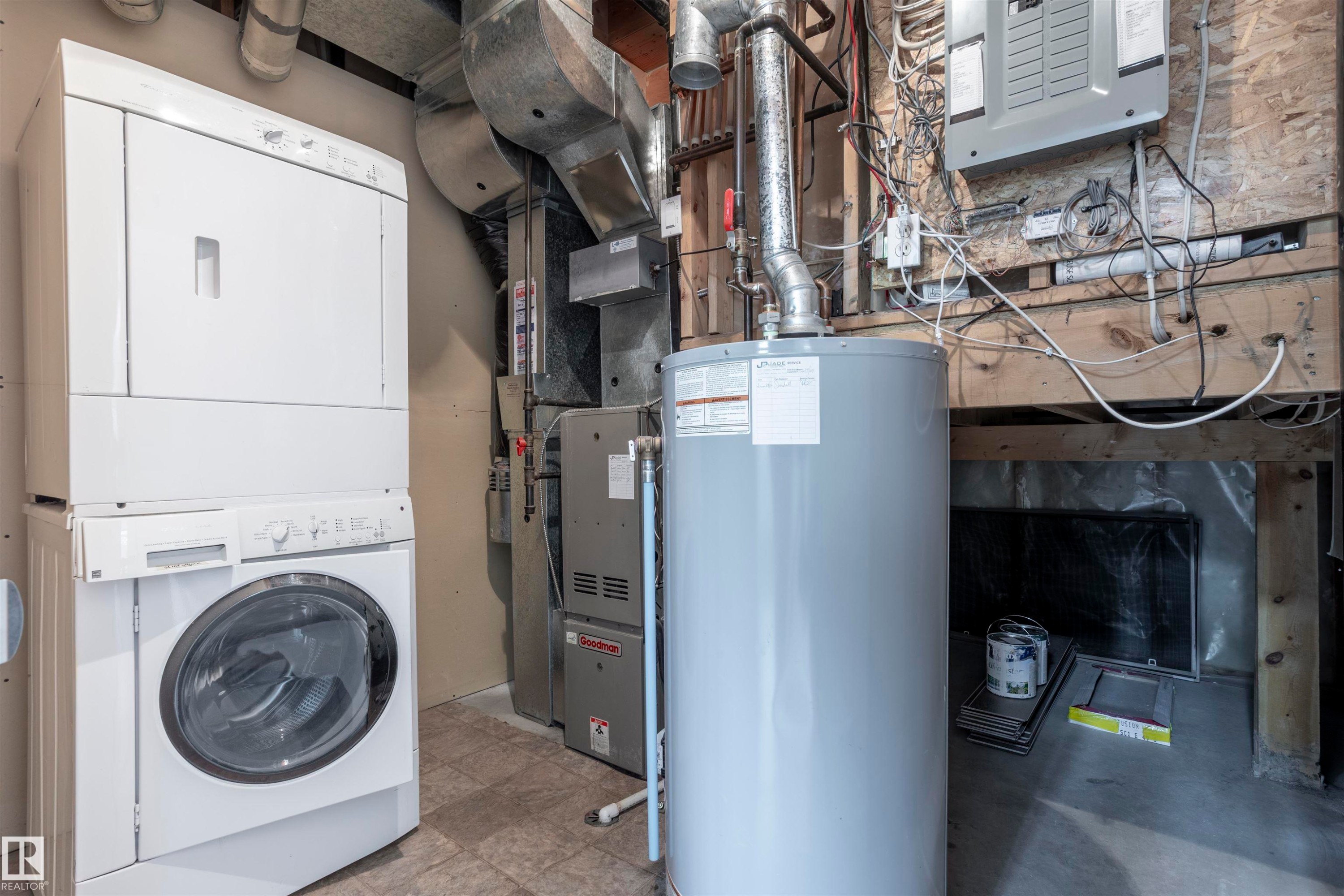Dedicated utility area featuring a stacked washer and dryer, a water heater, a furnace unit, and exposed ductwork - 738 Kananaskis Drive, Devon, AB - Indoor Photo Showing Laundry Room