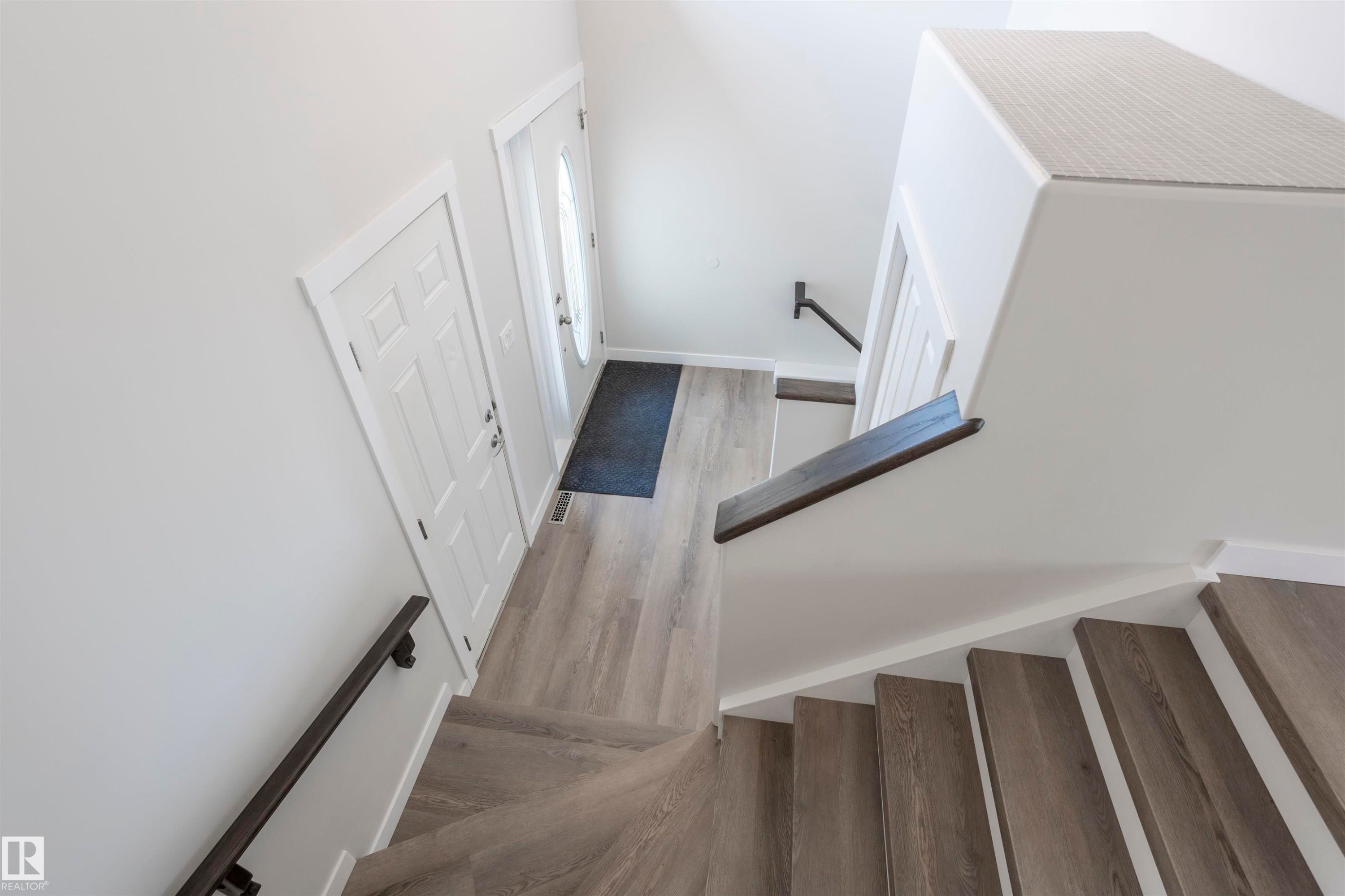 Entryway featuring wood-finish flooring, a paneled door, and a partially glass-paned door - 738 Kananaskis Drive, Devon, AB - Indoor Photo Showing Other Room