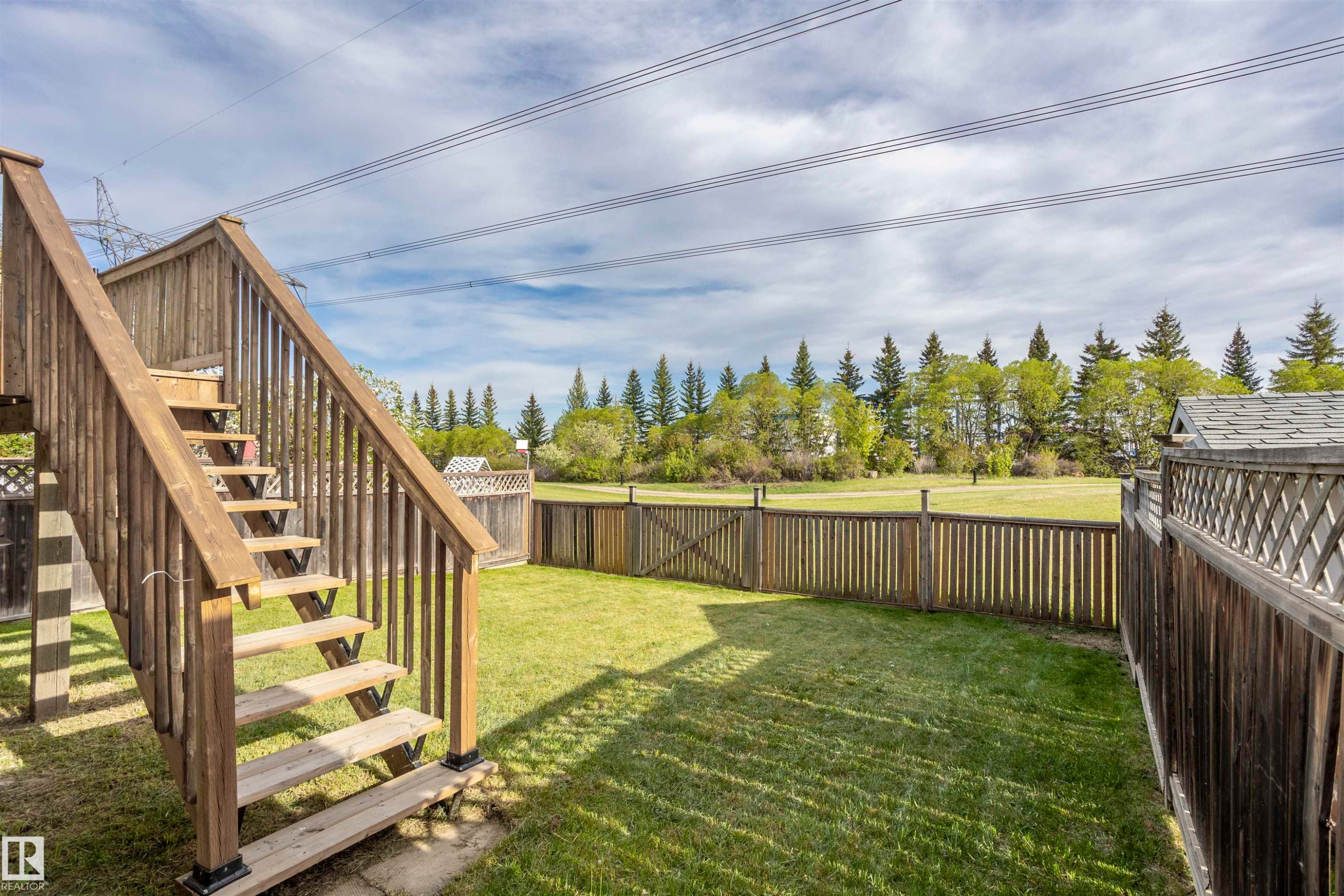 Expansive backyard featuring a wood-plank fence, manicured lawn, and a multi-level wood deck with stairs - 738 Kananaskis Drive, Devon, AB - Outdoor