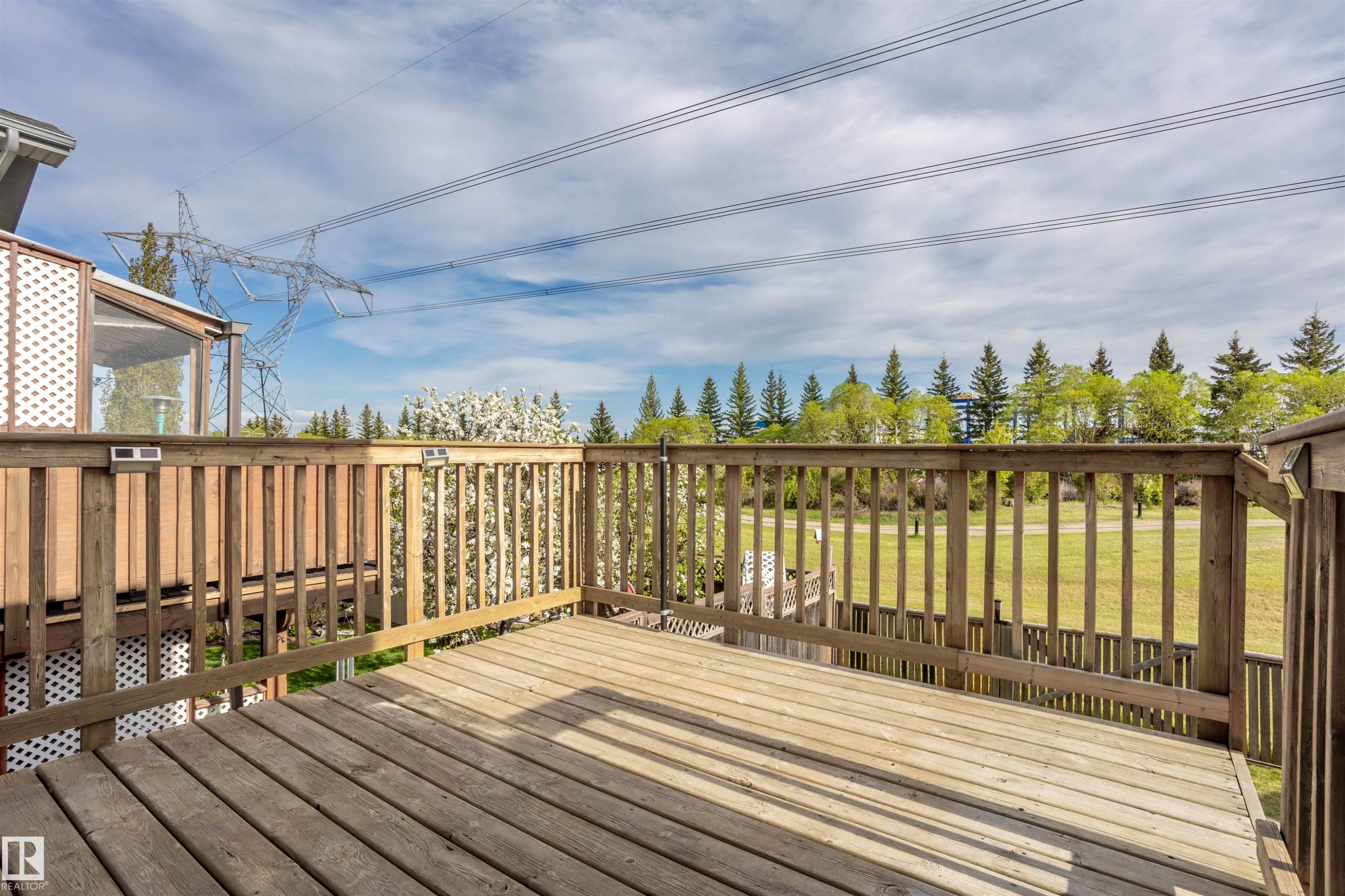 Outdoor wooden deck with railing, featuring a partial lattice privacy screen - 738 Kananaskis Drive, Devon, AB - Outdoor With Exterior