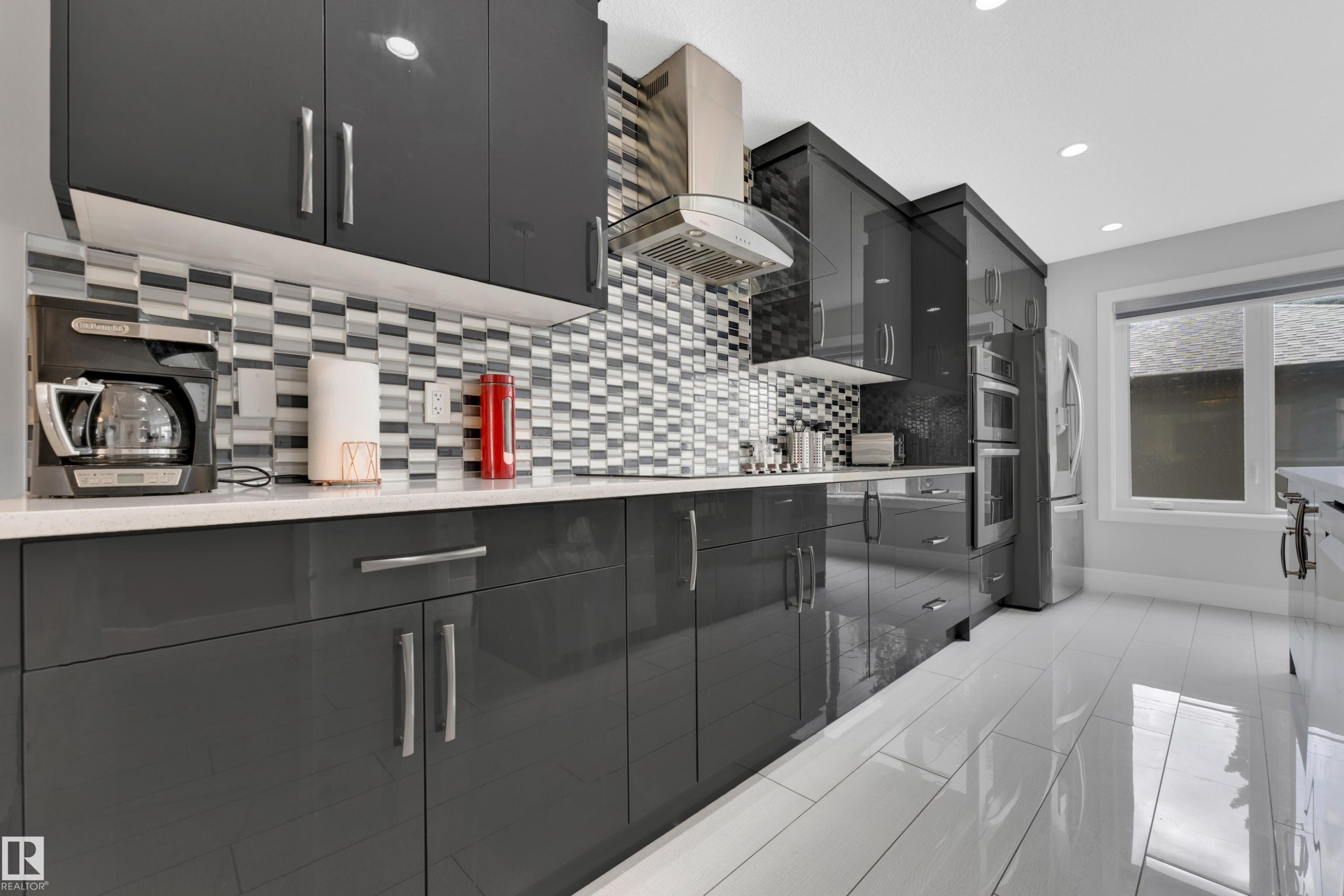 Contemporary kitchen featuring glossy dark cabinetry, a mosaic tile backsplash, and a stainless steel range hood - 9329 Connors Road, Edmonton, AB - Indoor Photo Showing Kitchen