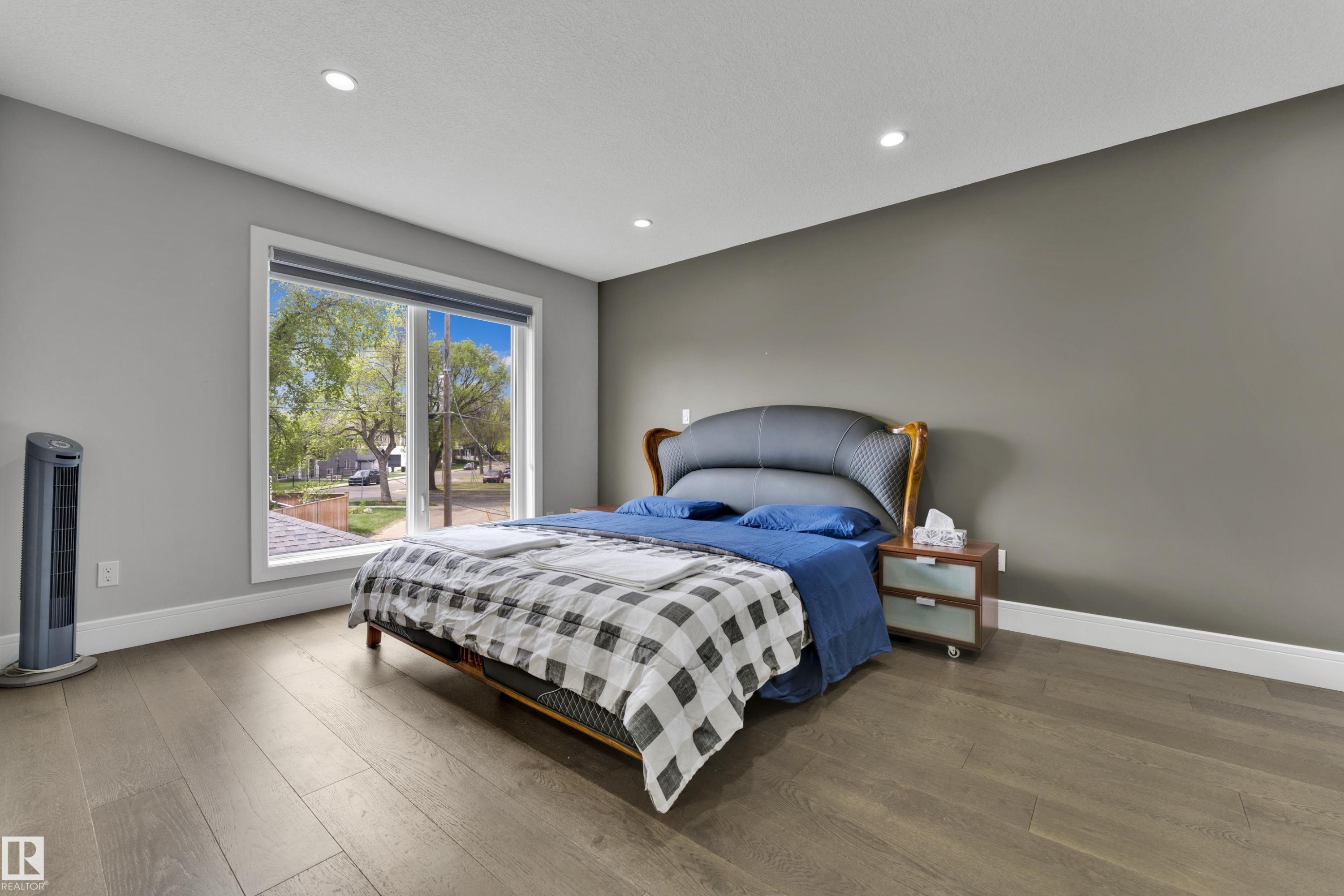 Spacious room featuring wood-finish flooring, a large window, recessed lighting, and a two-tone wall color scheme - 9329 Connors Road, Edmonton, AB - Indoor Photo Showing Bedroom