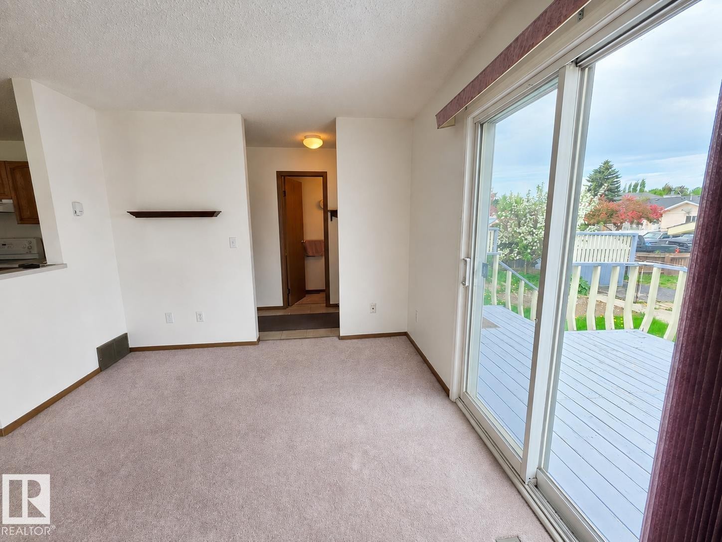 Light-colored carpeting throughout the main room, featuring a built-in wall shelf and white baseboards - 4005 55 Avenue, Whitecourt, AB - Indoor Photo Showing Other Room