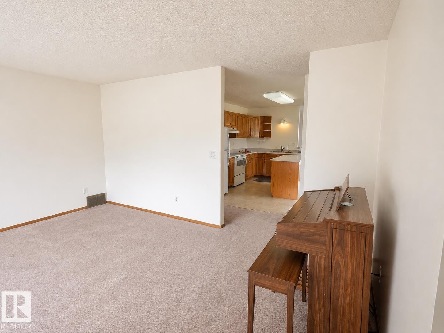 Expansive carpeted area with neutral walls and wood-finish trim, offering a versatile space - 4005 55 Avenue, Whitecourt, AB - Indoor Photo Showing Other Room