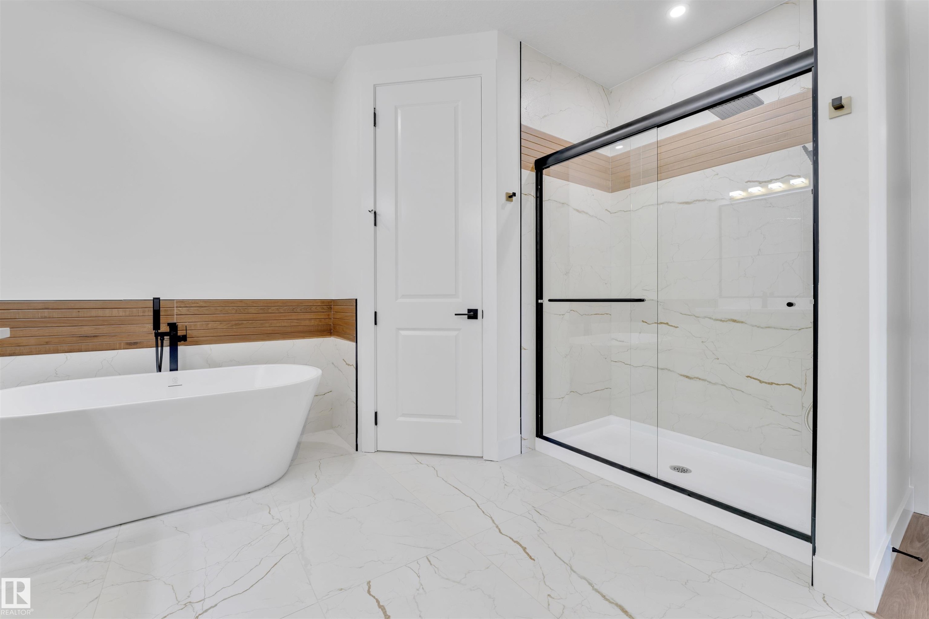 Modern bathroom featuring a freestanding soaking tub with a matte black faucet, a spacious glass-enclosed shower with a black frame, and wood-finish wall paneling - 2027 156 Avenue, Edmonton, AB - Indoor Photo Showing Bathroom