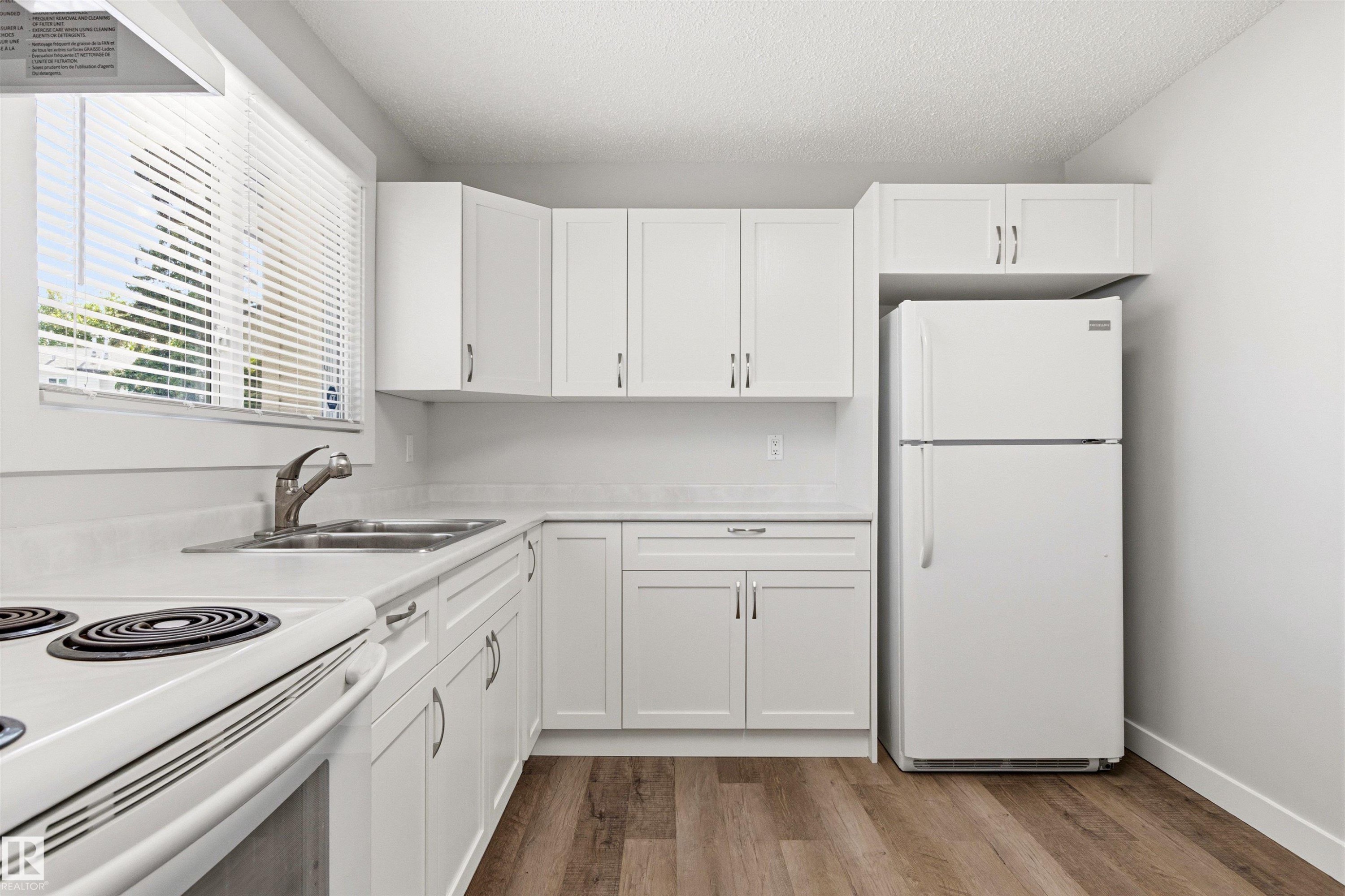 Kitchen featuring wood-finish flooring, white cabinetry, a double basin sink with a chrome faucet, a white oven, and a white refrigerator - 707 Clareview Road, Edmonton, AB - Indoor Photo Showing Kitchen With Double Sink