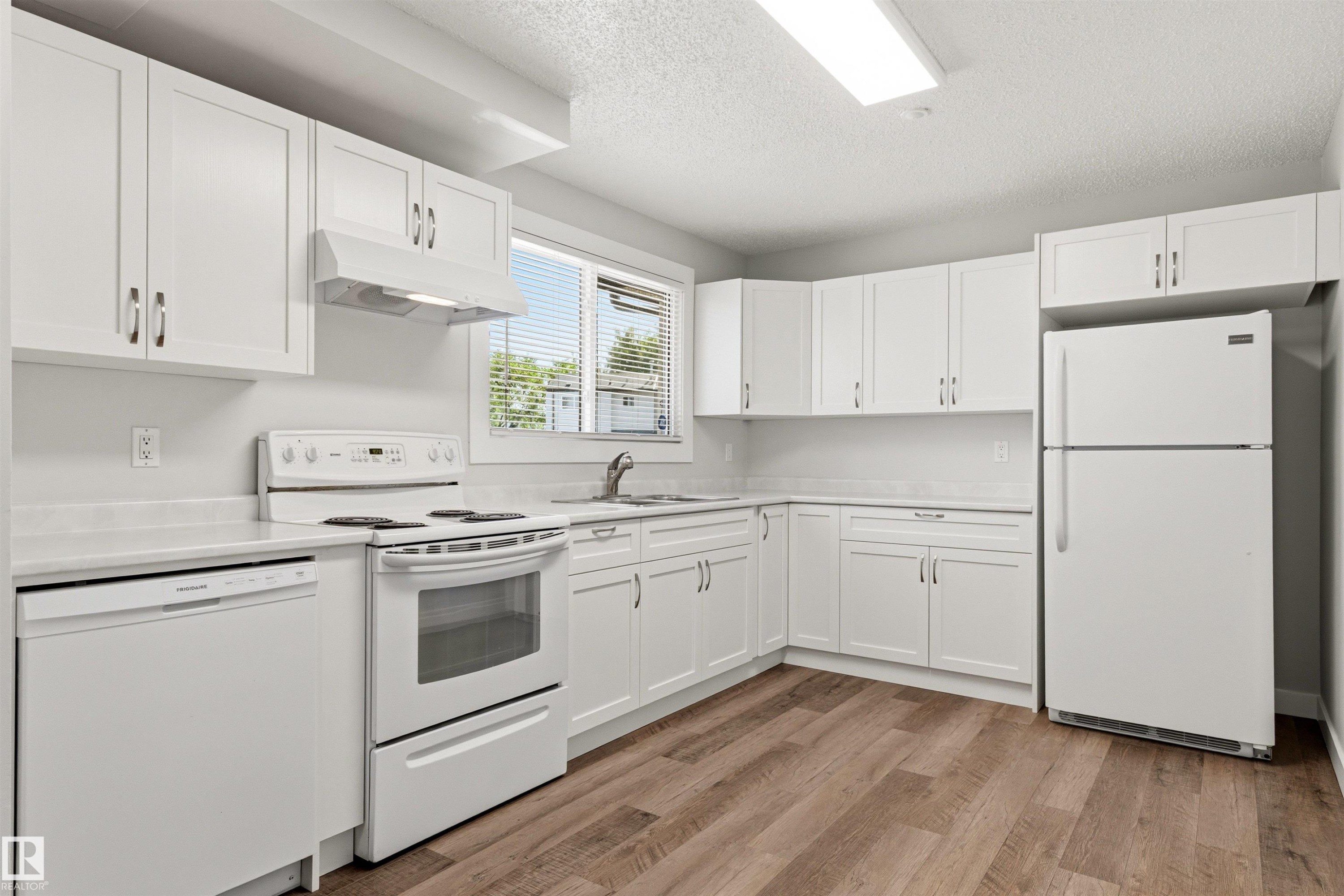 Kitchen featuring white cabinetry, white appliances, wood-finish flooring, white countertops, and a window with blinds - 707 Clareview Road, Edmonton, AB - Indoor Photo Showing Kitchen