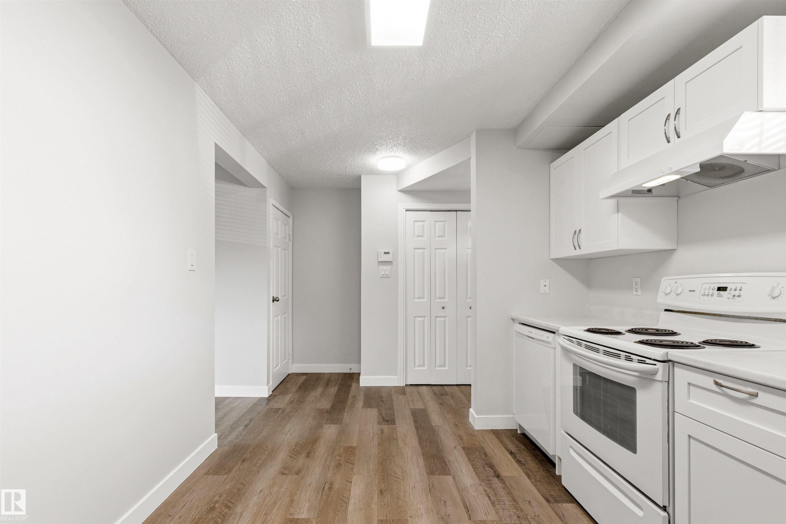 Kitchen featuring wood-finish flooring, white cabinetry, a white electric range, and a white dishwasher - 707 Clareview Road, Edmonton, AB - Indoor Photo Showing Kitchen