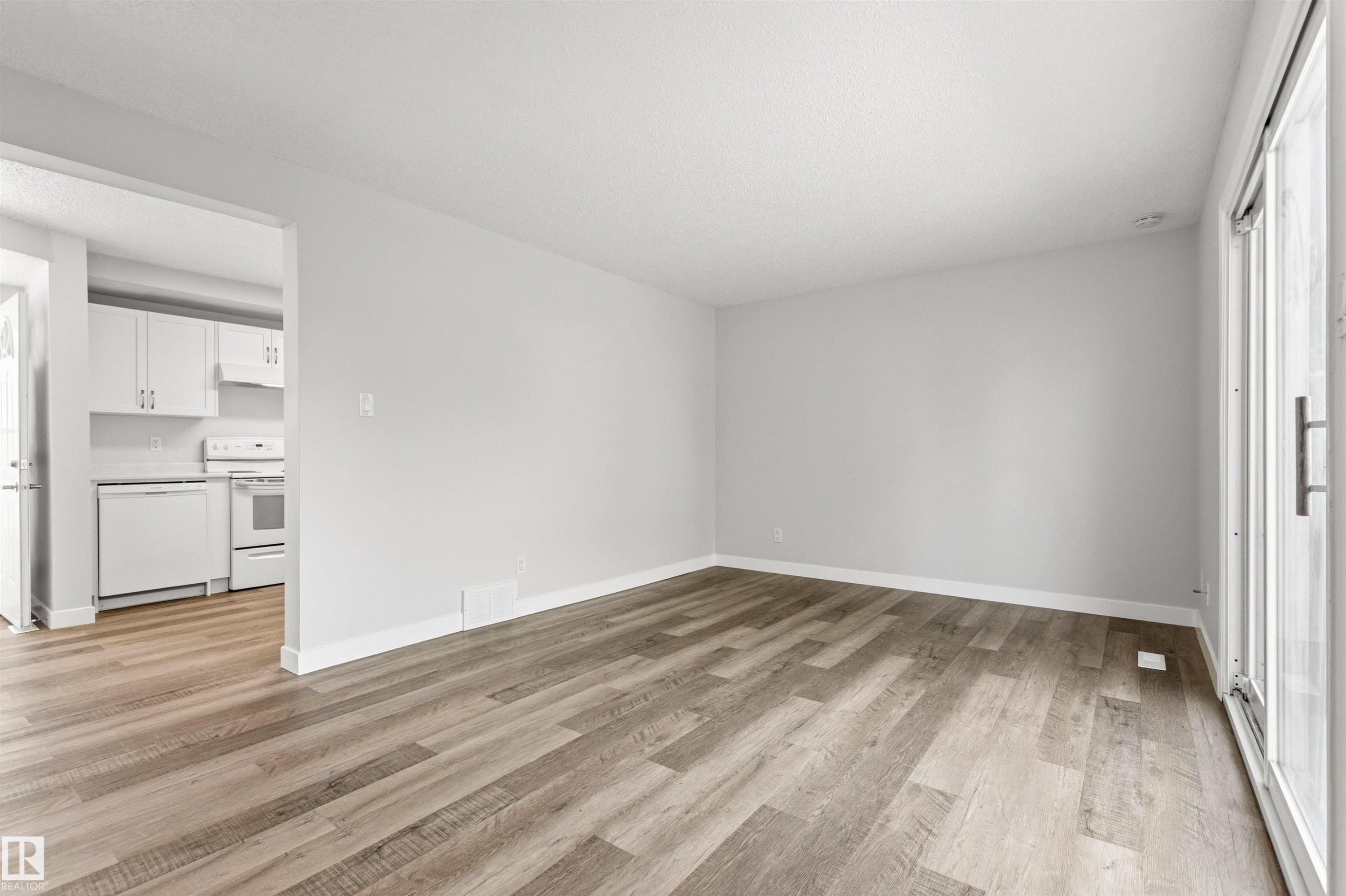 Spacious room featuring wood-finish flooring, light grey walls, and white baseboards - 707 Clareview Road, Edmonton, AB - Indoor Photo Showing Other Room