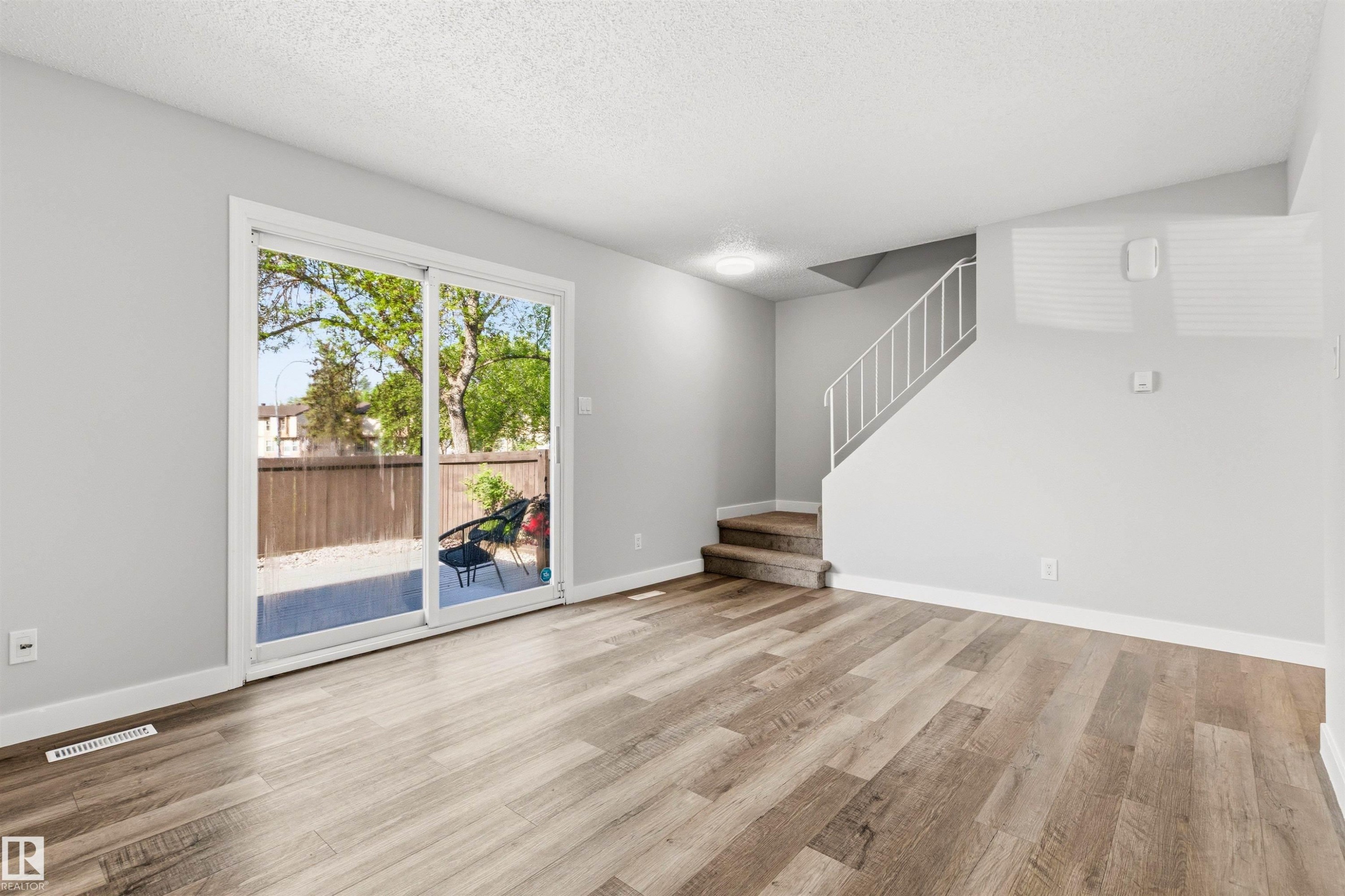 Spacious living area featuring wood-finish flooring, light gray walls, and a white ceiling - 707 Clareview Road, Edmonton, AB - Indoor