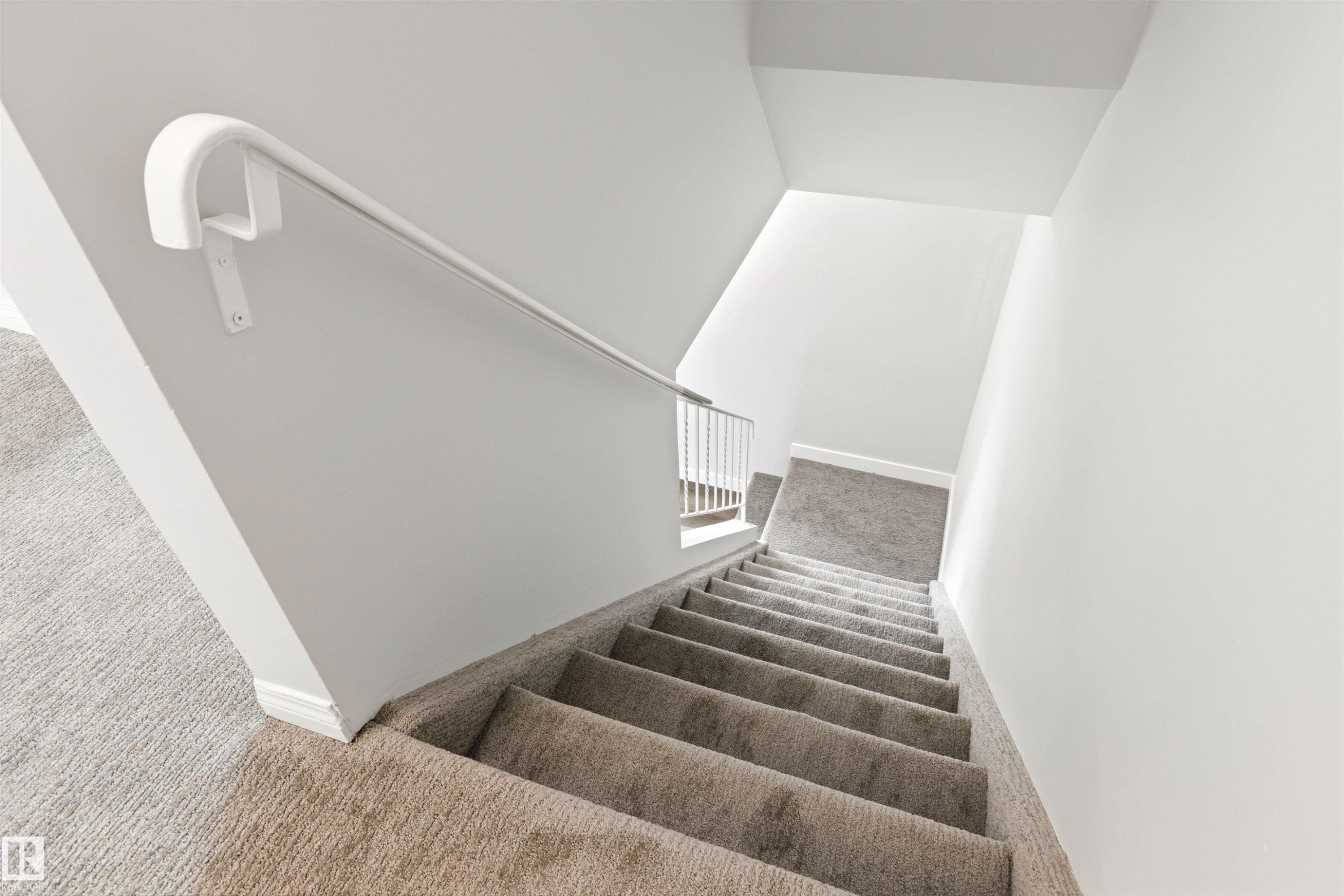 Carpeted staircase featuring a painted white handrail and white wall finishes - 707 Clareview Road, Edmonton, AB - Indoor Photo Showing Other Room