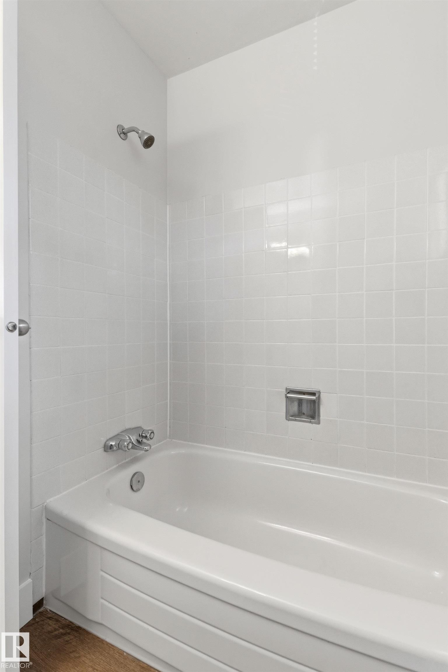 White tiled shower surround with a built-in tub, chrome shower head, and chrome tub fixtures - 707 Clareview Road, Edmonton, AB - Indoor Photo Showing Bathroom