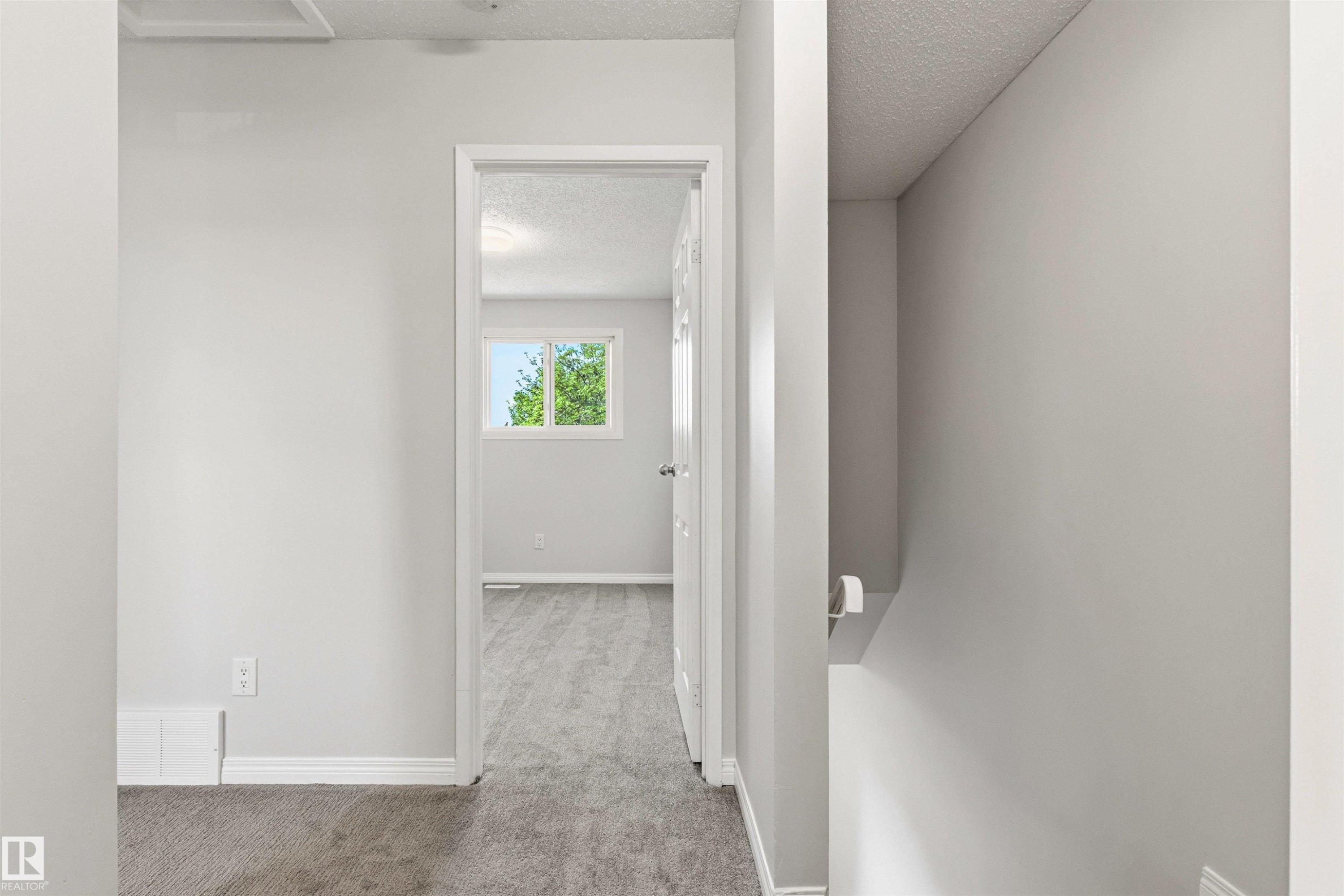 Interior doorway with white trim opens to a room featuring a window with green foliage outside - 707 Clareview Road, Edmonton, AB - Indoor Photo Showing Other Room