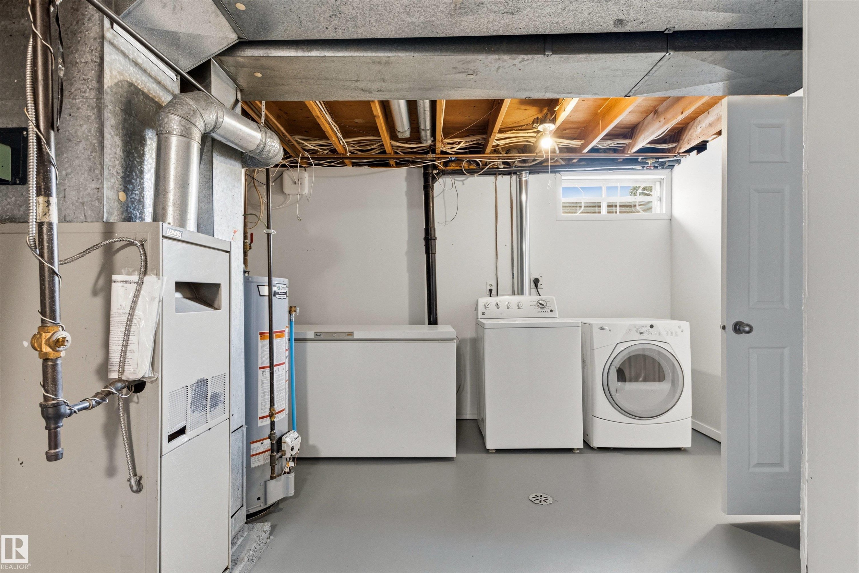 Utility area featuring a washer and dryer, painted concrete flooring, recessed window, and exposed ceiling joists - 707 Clareview Road, Edmonton, AB - Indoor Photo Showing Laundry Room