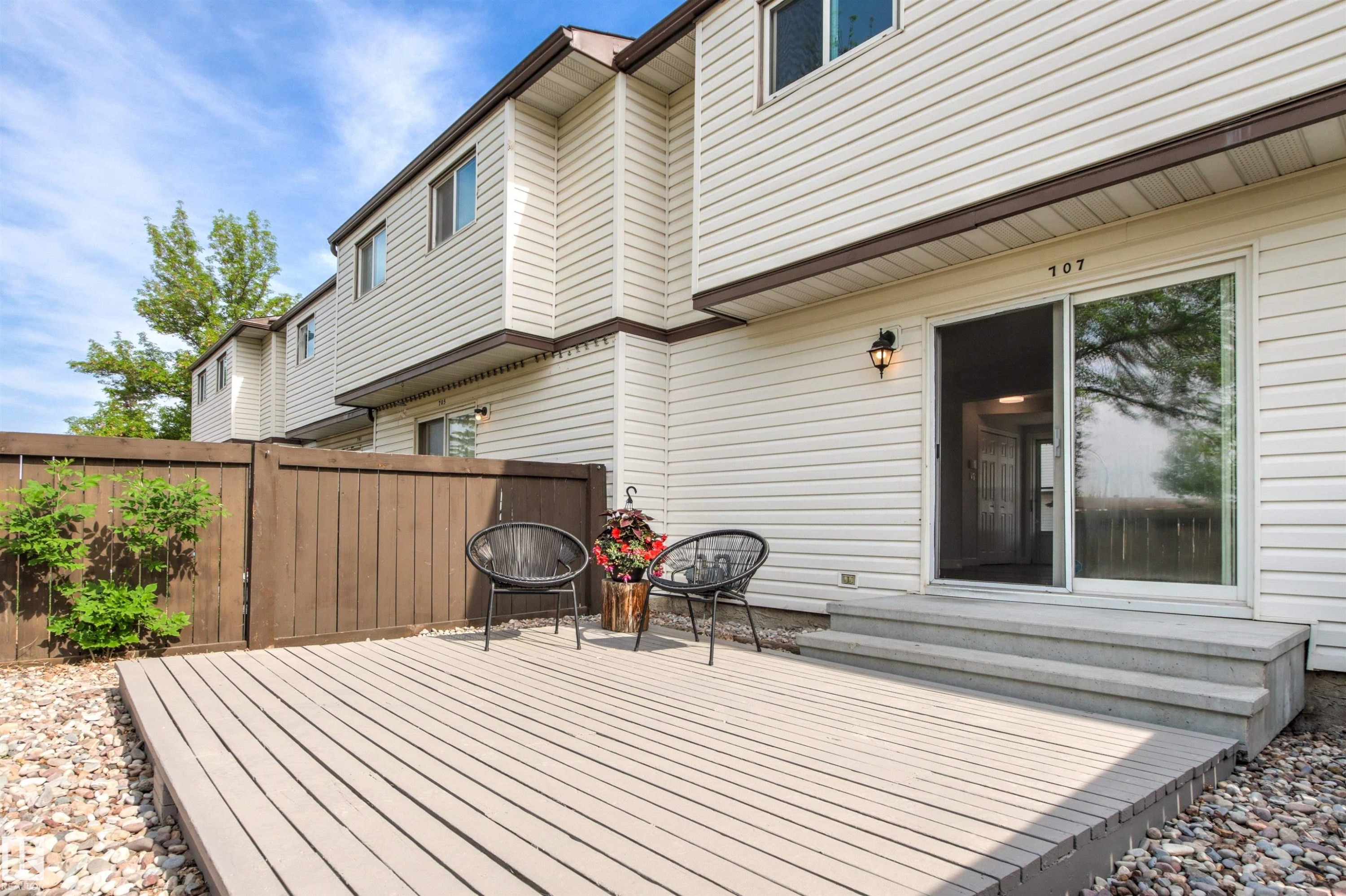 Ground-level deck with textured composite decking, framed by a wood privacy fence - 707 Clareview Road, Edmonton, AB - Outdoor With Deck Patio Veranda With Exterior