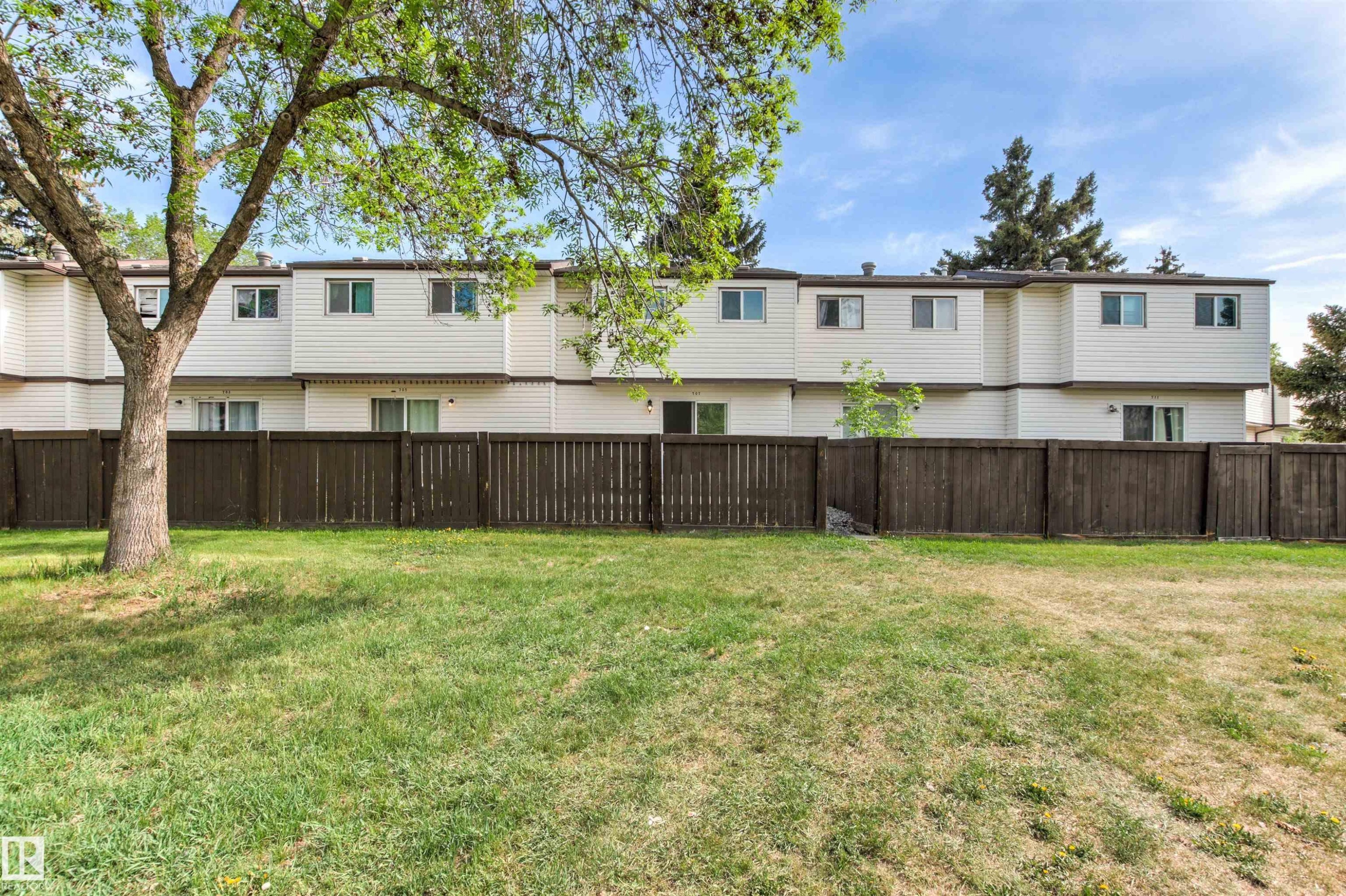 Expansive grassy area bordered by a tall wooden fence - 707 Clareview Road, Edmonton, AB - Outdoor