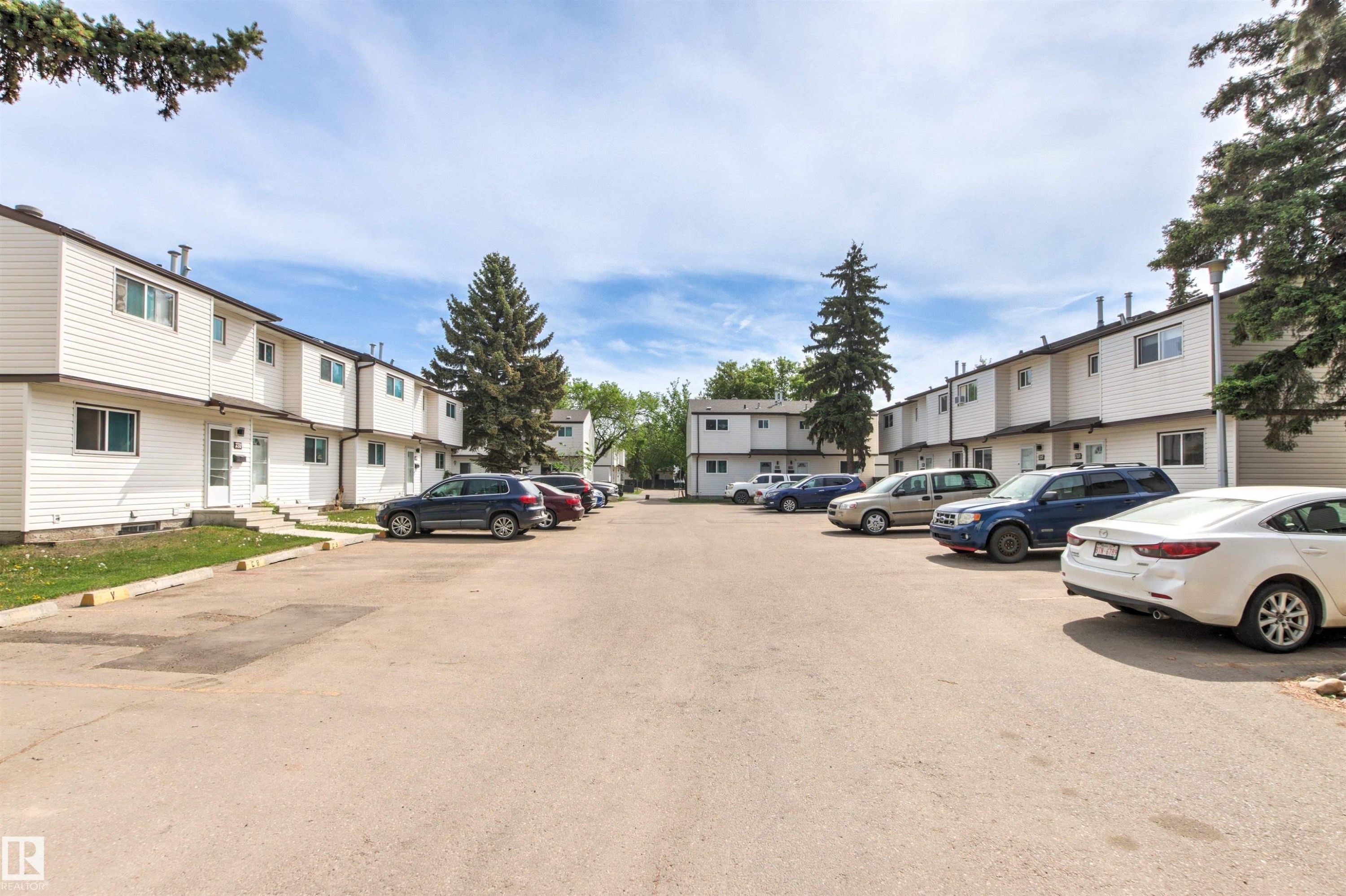 Townhome complex featuring white siding exteriors, multiple units, and mature trees - 707 Clareview Road, Edmonton, AB - Outdoor