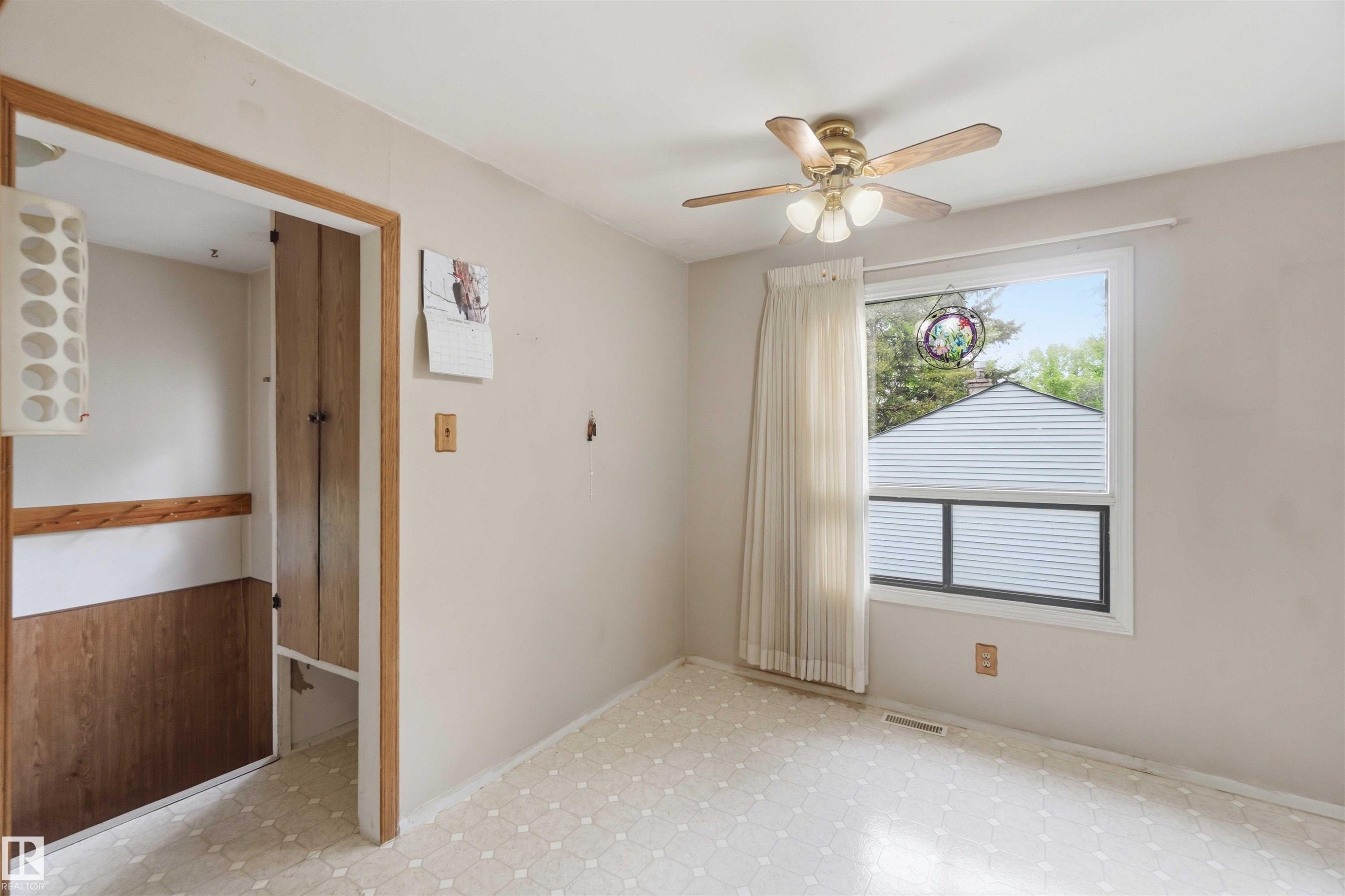 Bright room featuring a ceiling fan, a window with natural light, and patterned vinyl flooring - 16 Michigan Street, Devon, AB - Indoor Photo Showing Other Room
