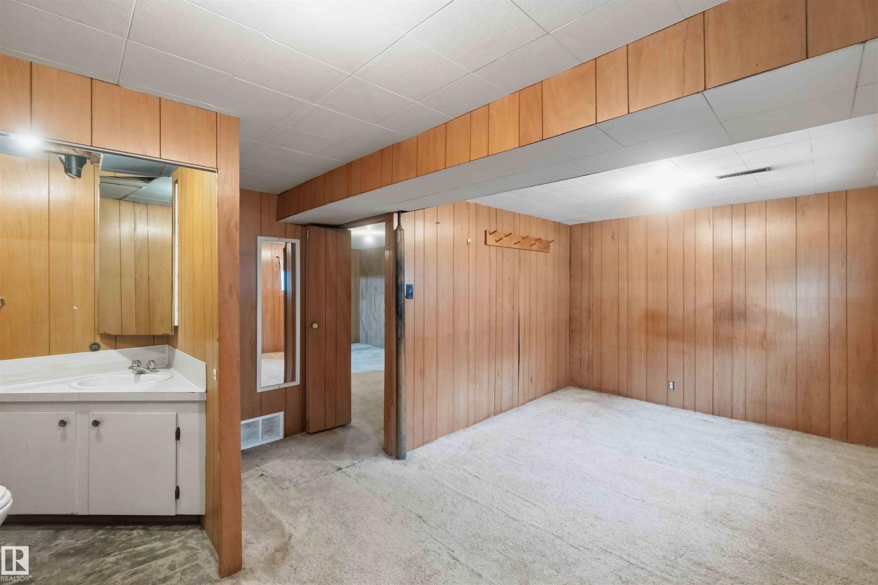 Room featuring wood-paneled walls, light-colored carpet flooring, and a drop ceiling - 16 Michigan Street, Devon, AB - Indoor