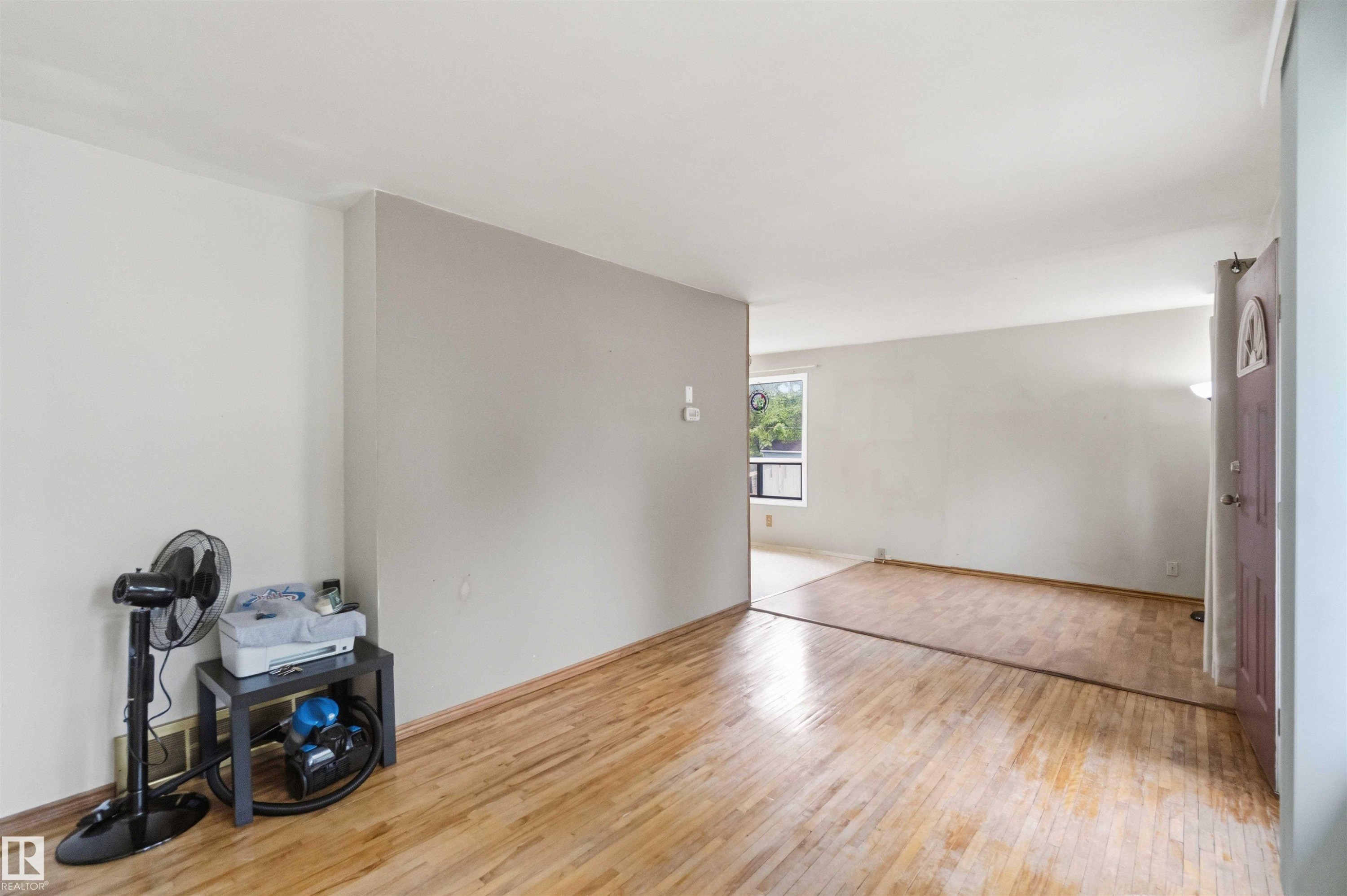Bright interior space featuring wood-finish flooring, light-toned wall paint, and a window providing natural illumination - 16 Michigan Street, Devon, AB - Indoor Photo Showing Other Room