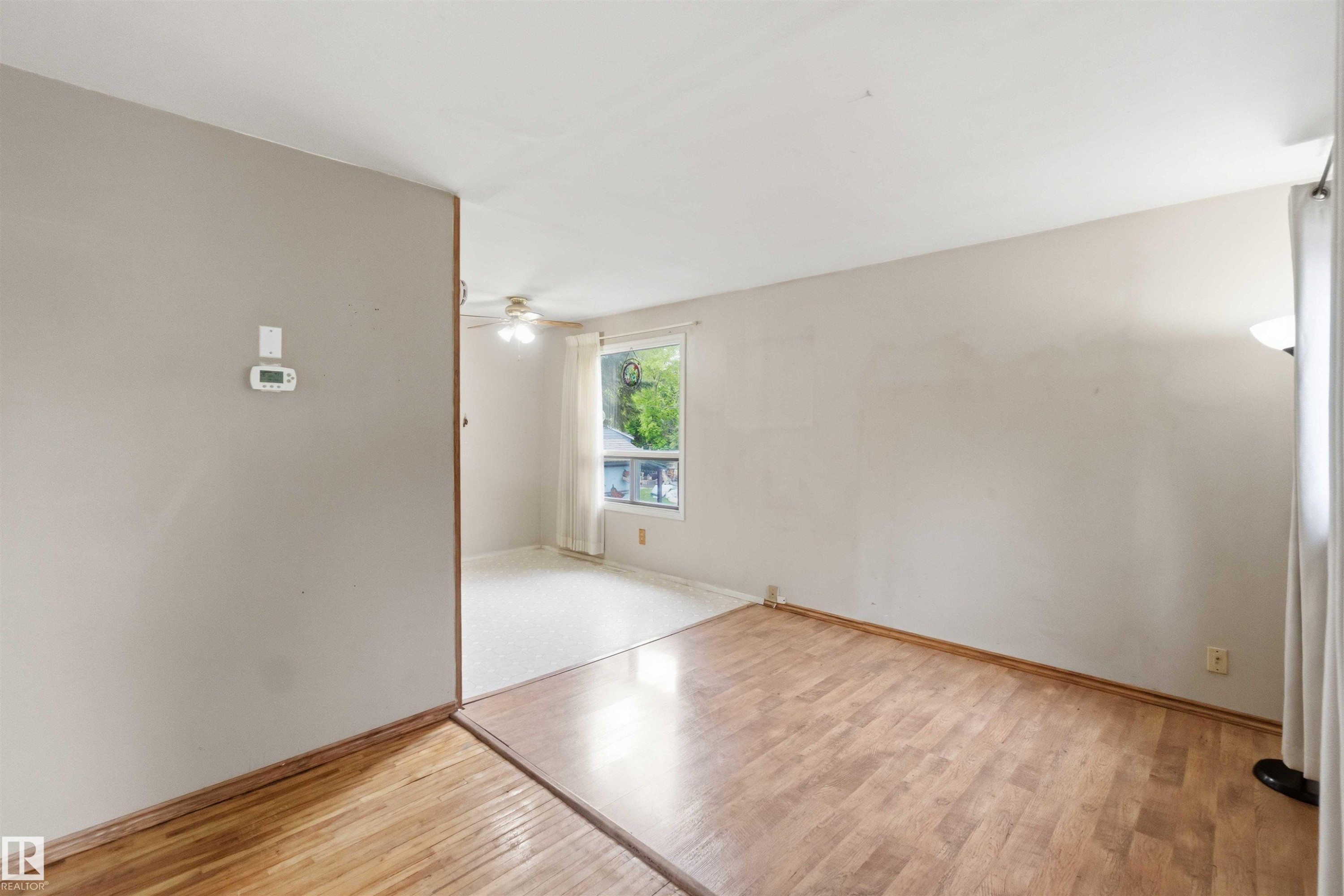 Interior room featuring wood-finish flooring, light-toned walls, and a contrasting wall with a thermostat - 16 Michigan Street, Devon, AB - Indoor Photo Showing Other Room