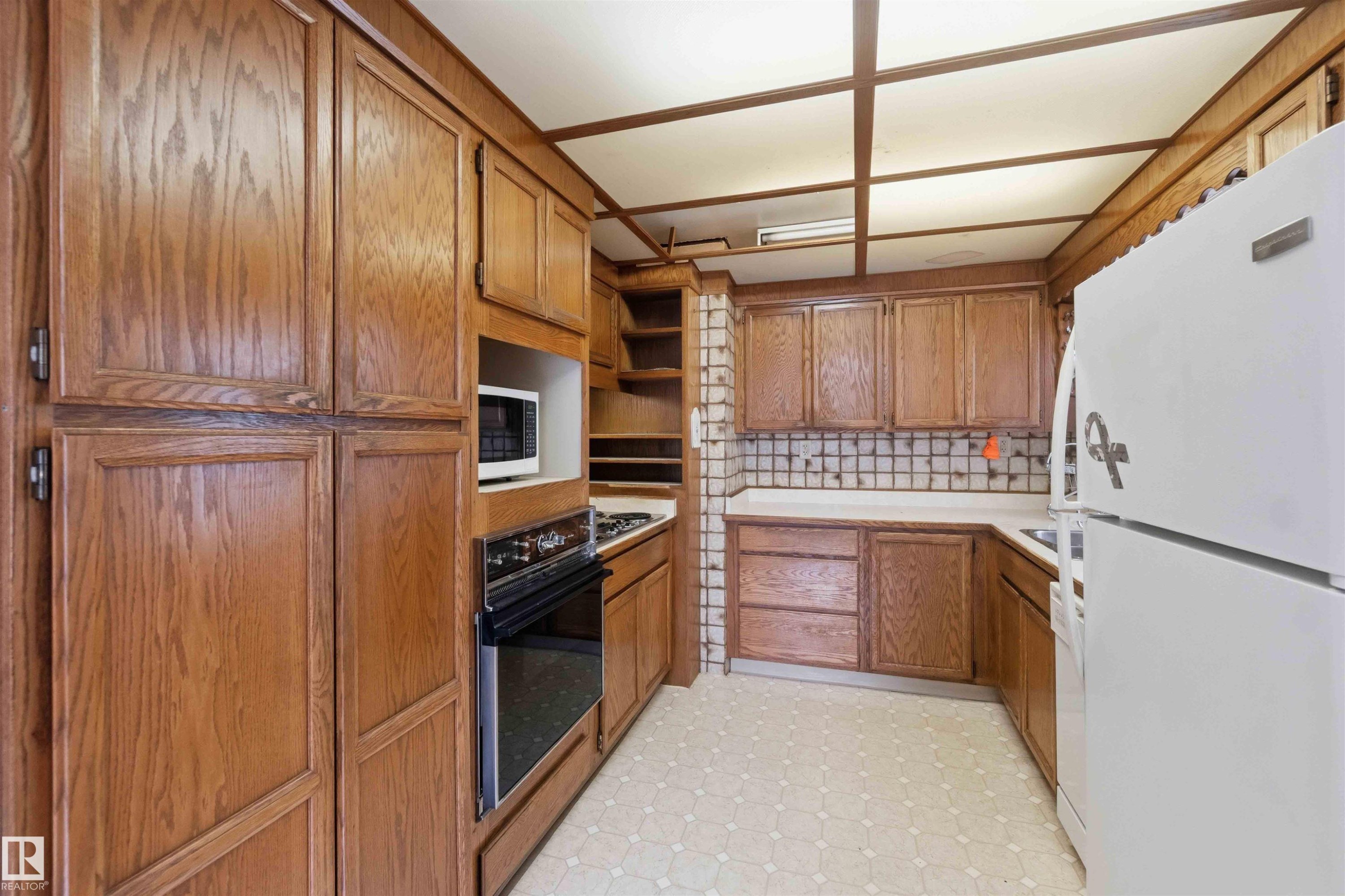 Kitchen featuring extensive wood cabinetry, white laminate countertops, and patterned vinyl flooring - 16 Michigan Street, Devon, AB - Indoor Photo Showing Kitchen