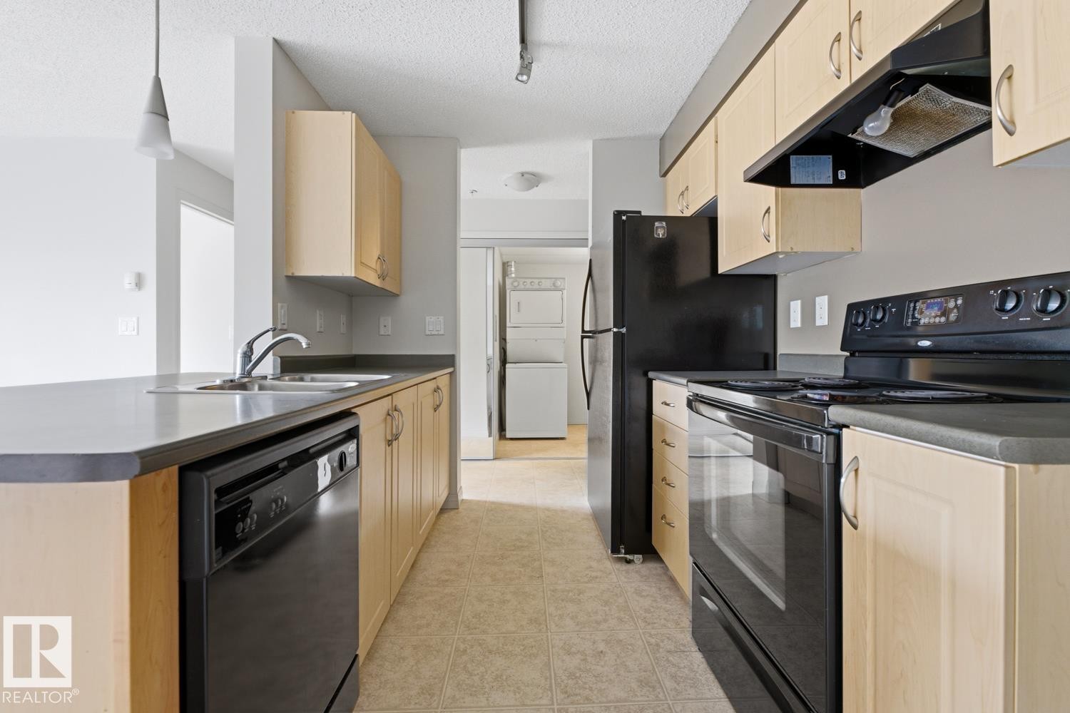 Kitchen featuring light wood-finish cabinetry, black appliances, a double basin stainless steel sink, and a dishwasher - #312 13908 136 St Nw, Edmonton, AB - Indoor Photo Showing Kitchen With Double Sink