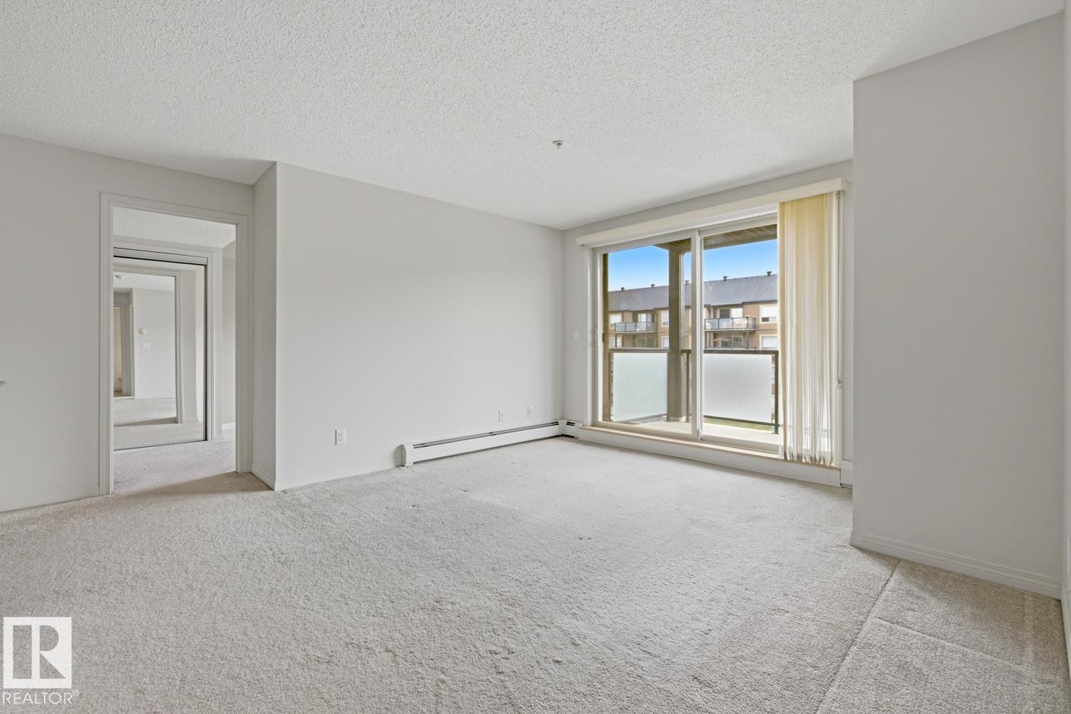 Spacious room featuring light-toned carpeting and neutral wall paint - #312 13908 136 St Nw, Edmonton, AB - Indoor Photo Showing Other Room