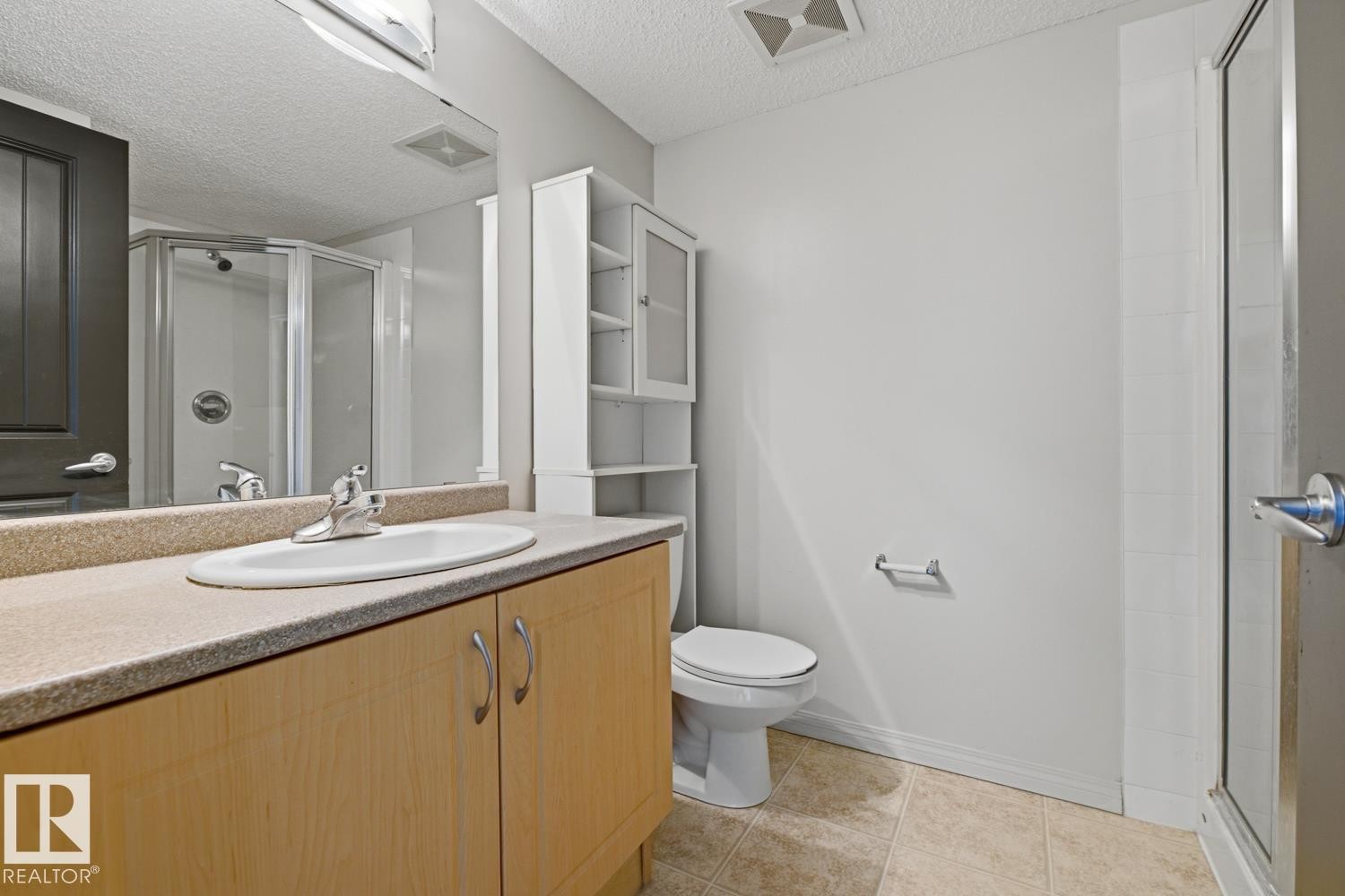 Bathroom vanity featuring a light wood-finish cabinet with a neutral-toned countertop and an oval undermount sink - #312 13908 136 St Nw, Edmonton, AB - Indoor Photo Showing Bathroom