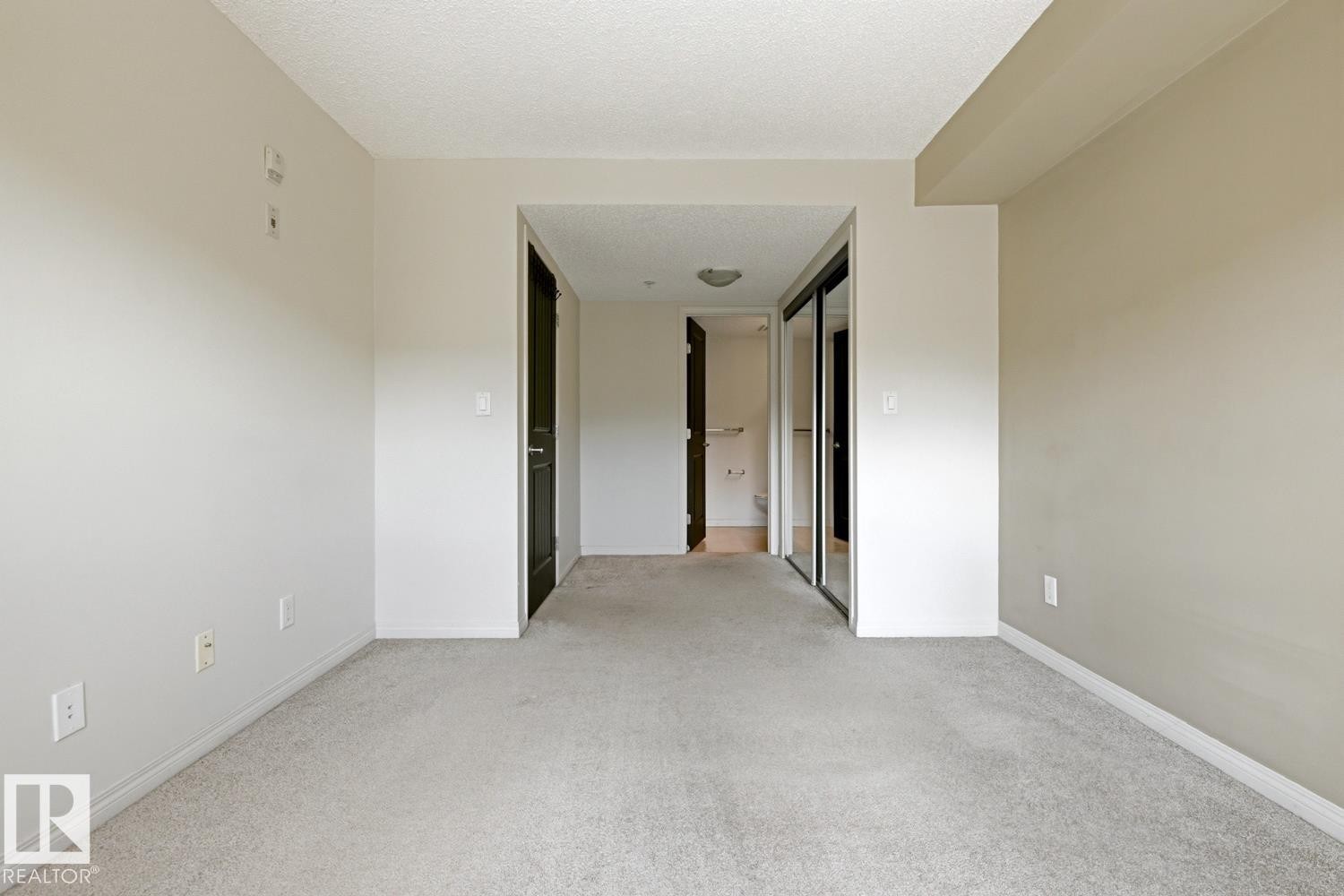 Neutral-toned interior featuring wall-to-wall carpeting, white baseboards, and a lightly textured ceiling - #312 13908 136 St Nw, Edmonton, AB - Indoor Photo Showing Other Room