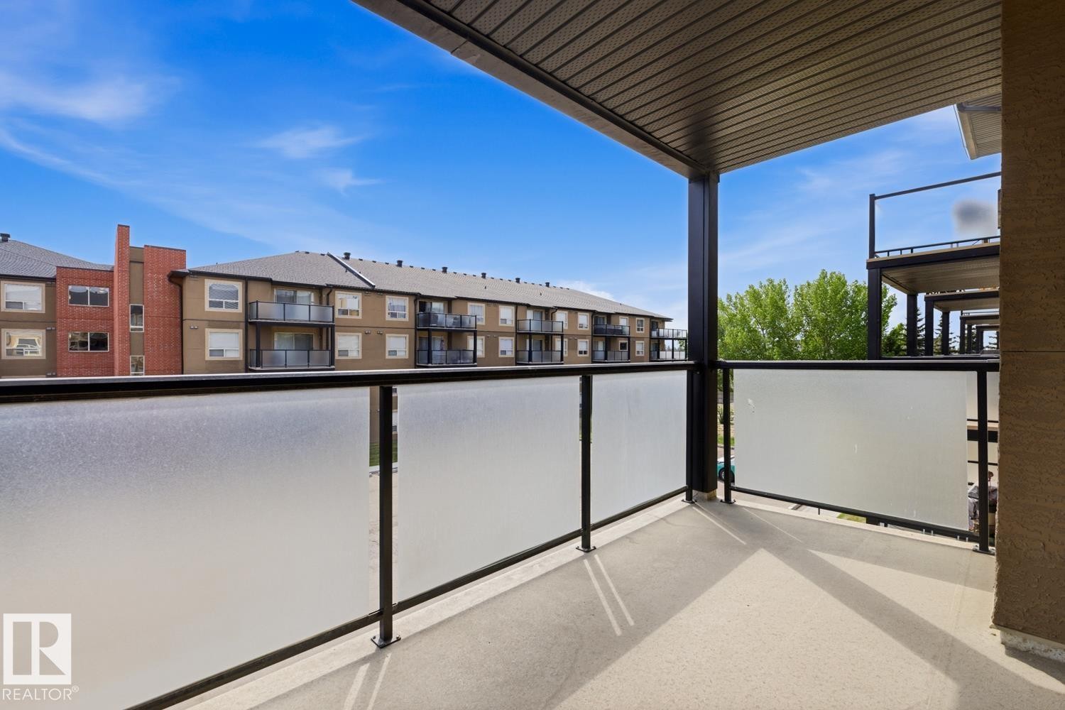 Private balcony featuring frosted glass panels and black railings - #312 13908 136 St Nw, Edmonton, AB - Outdoor With Balcony With Exterior